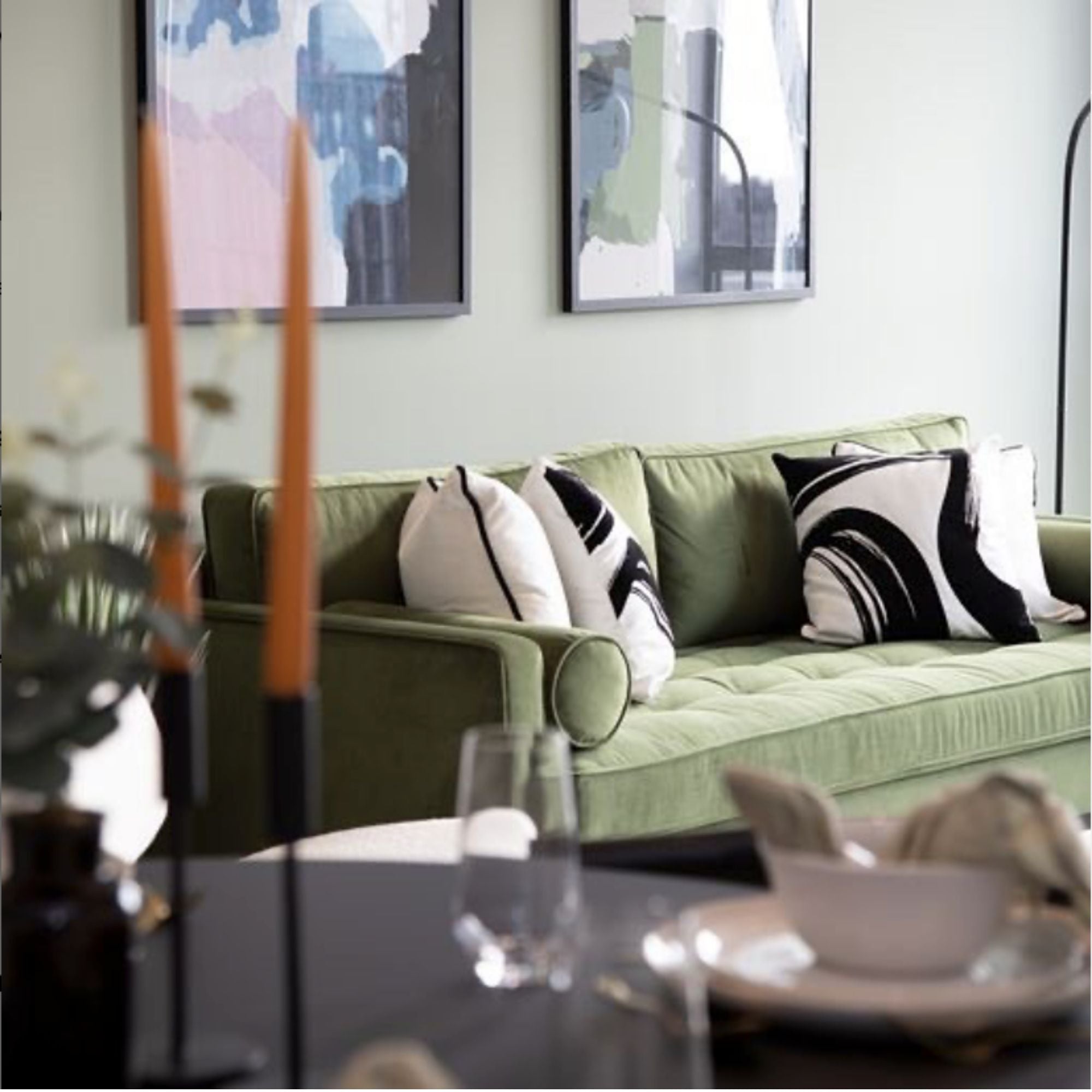 framed abstract wall art on a wall above a green modern sofa in a styled living room space