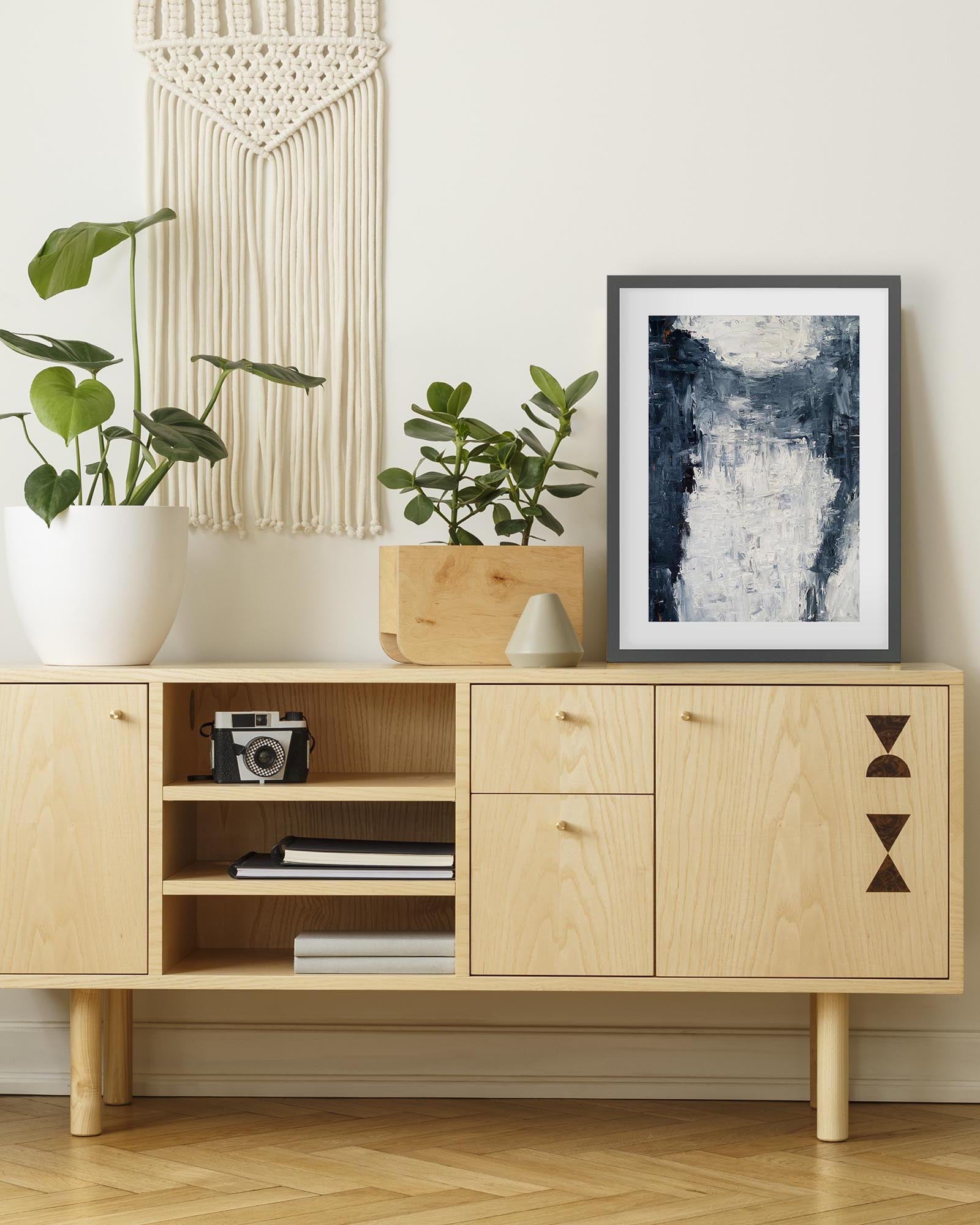 Wooden cabinet with decorative items in a room with plants and wall art.