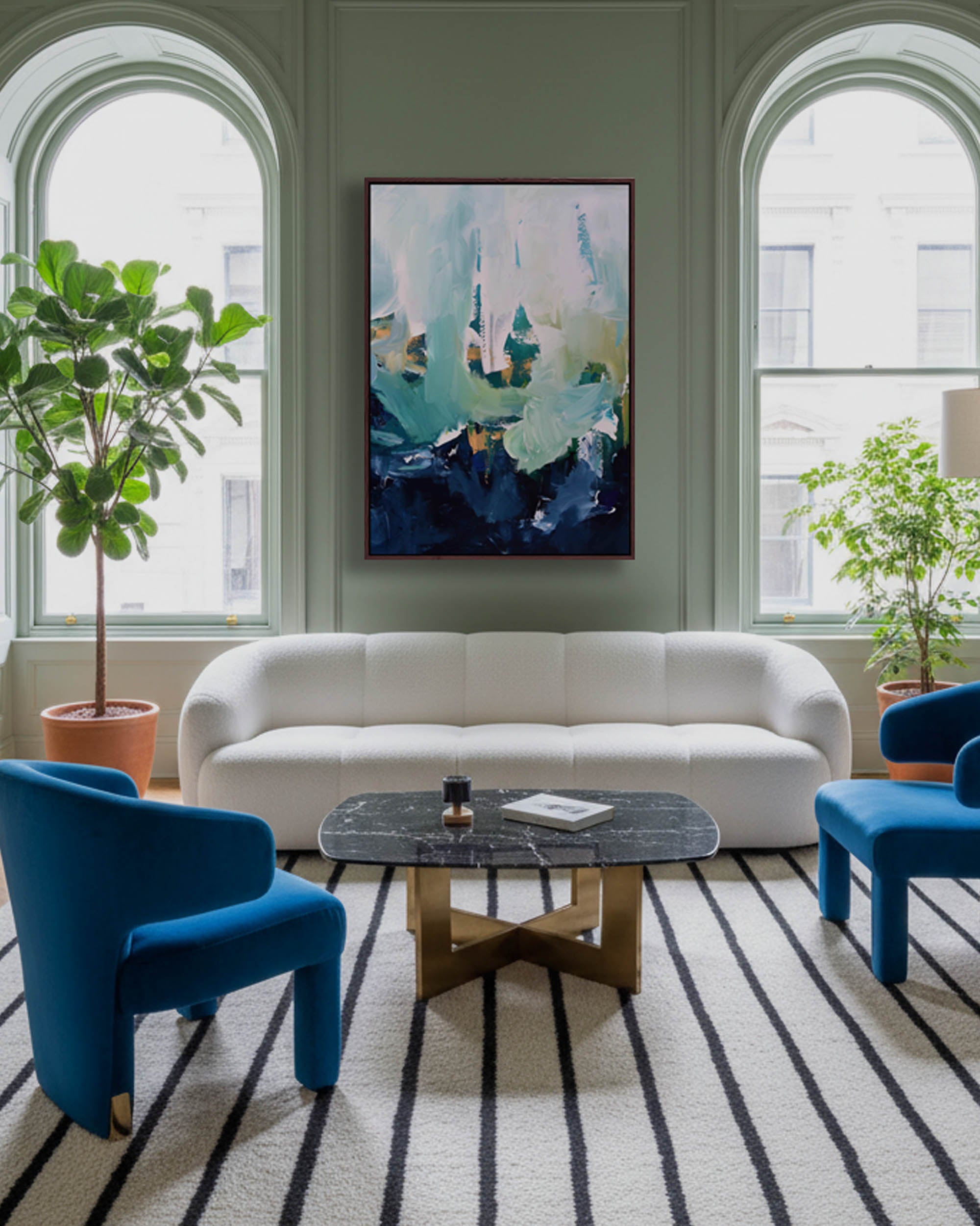 Modern living room with a white sofa, blue chairs, and abstract art on the wall.