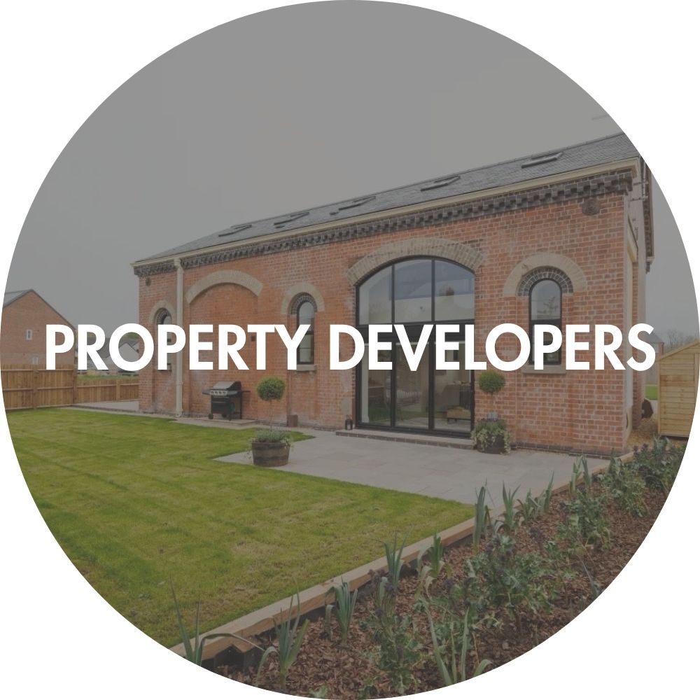 Modern eco build grand design with red brick building with large windows and a garden, modern sustainable development built by property developer, labeled 'PROPERTY DEVELOPERS'.