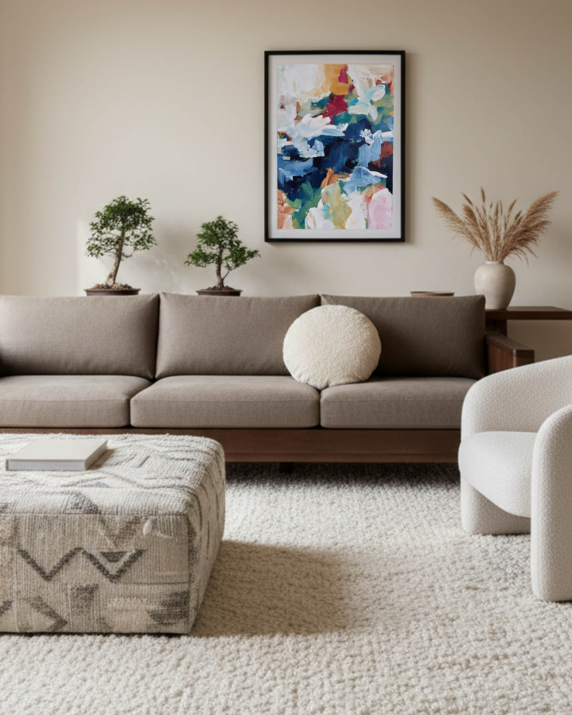 Modern living room with a gray sofa, patterned ottoman, and colorful abstract painting on the wall.