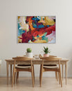 Dining room with a wooden table and chairs, plants, and a colorful abstract painting on the wall.