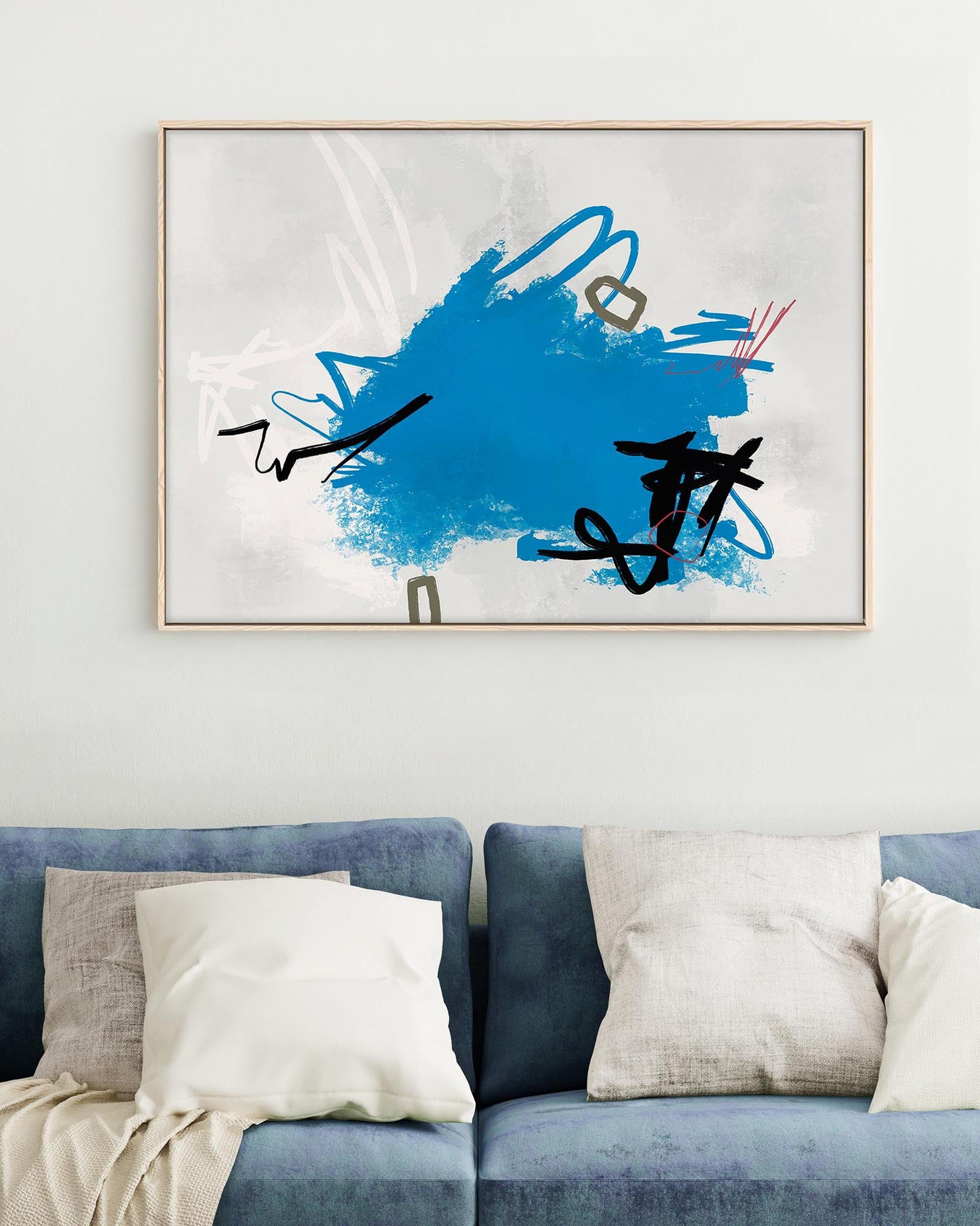 Abstract art piece with blue and black design on a wall above a blue sofa.
