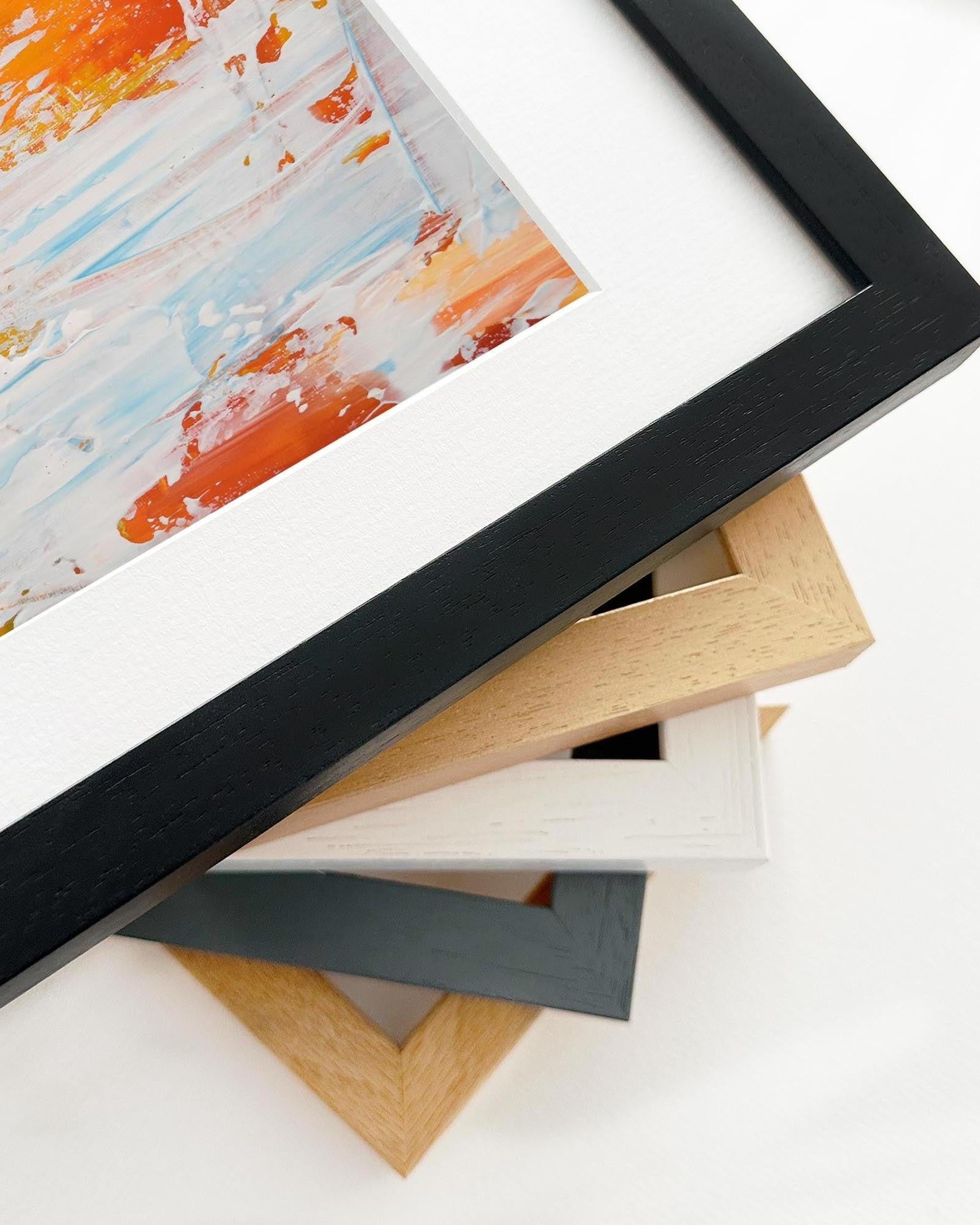 Stack of various picture frames on a white surface with a partially visible painting.