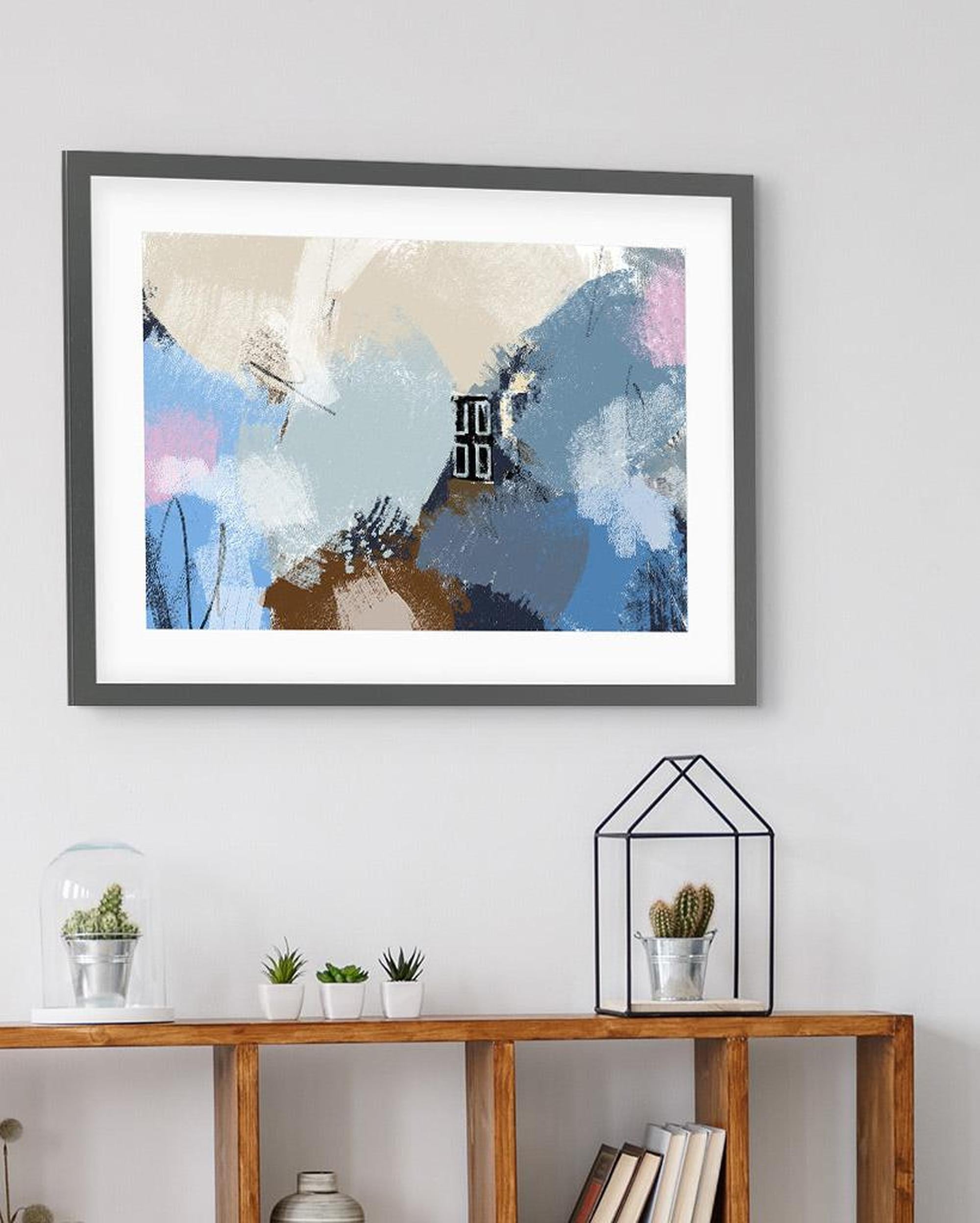 Framed abstract art piece on a wall above a wooden console table with decorative items.