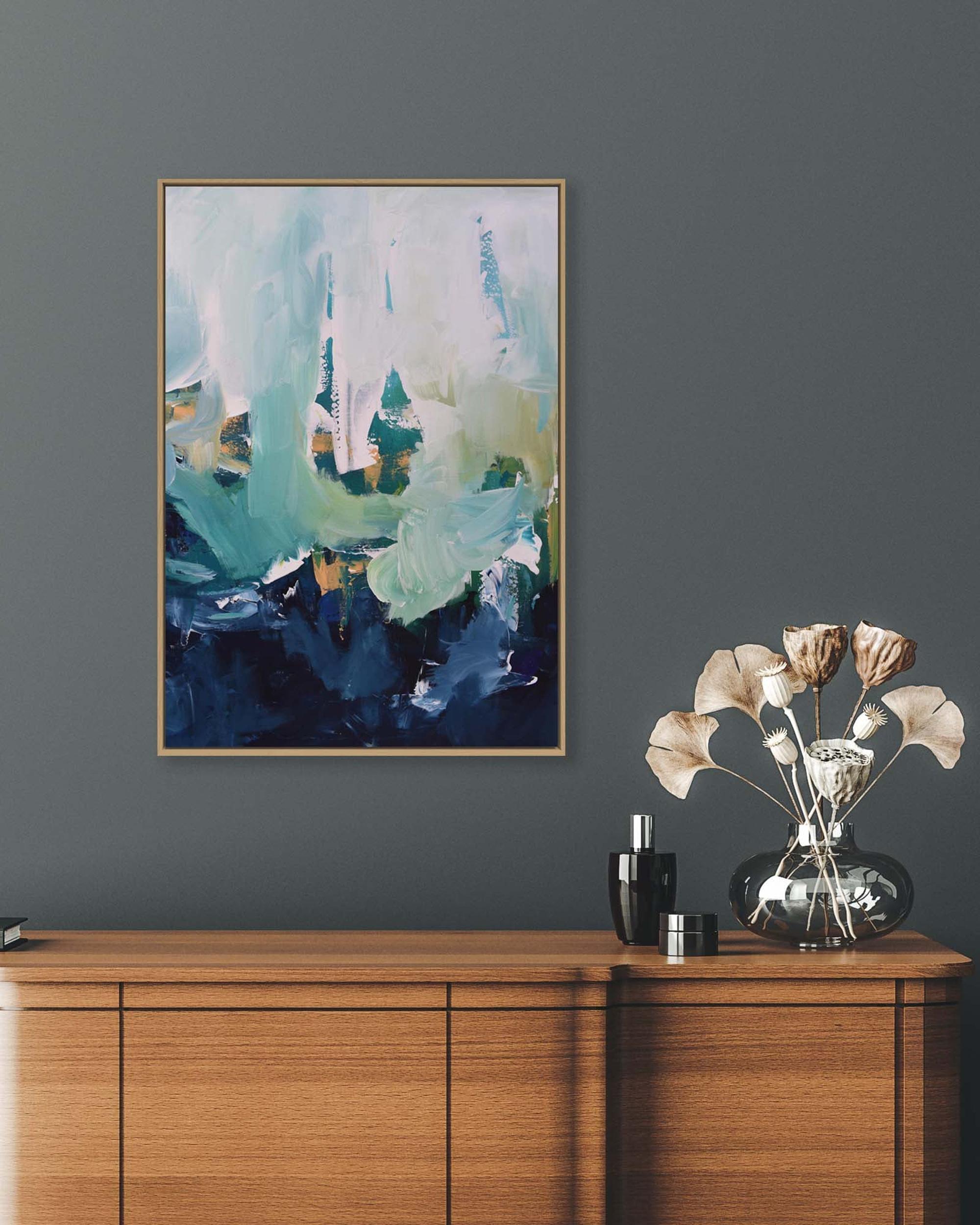 Abstract painting on a gray wall above a wooden cabinet with decorative items.