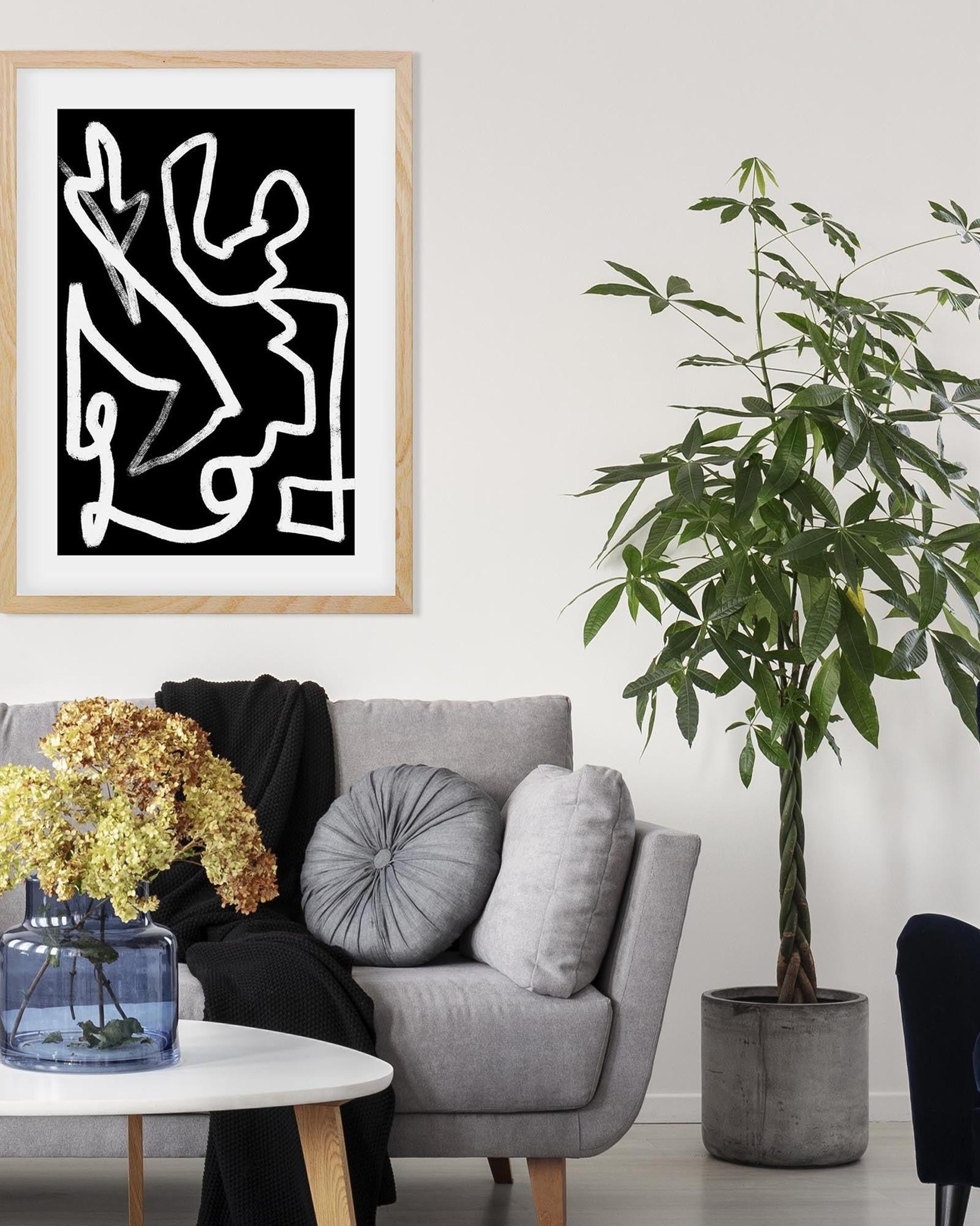 Living room with a gray sofa, plant, and abstract artwork on the wall.