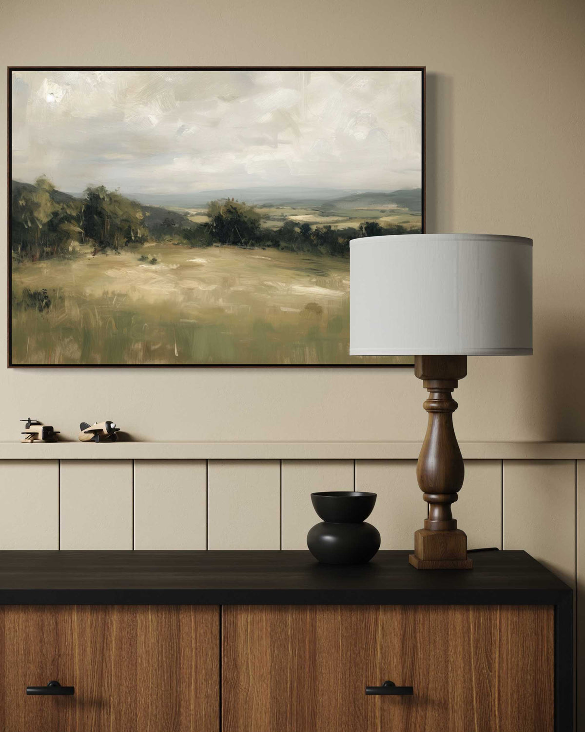 Room interior with a large landscape painting, lamp, and decorative items on a wooden cabinet.