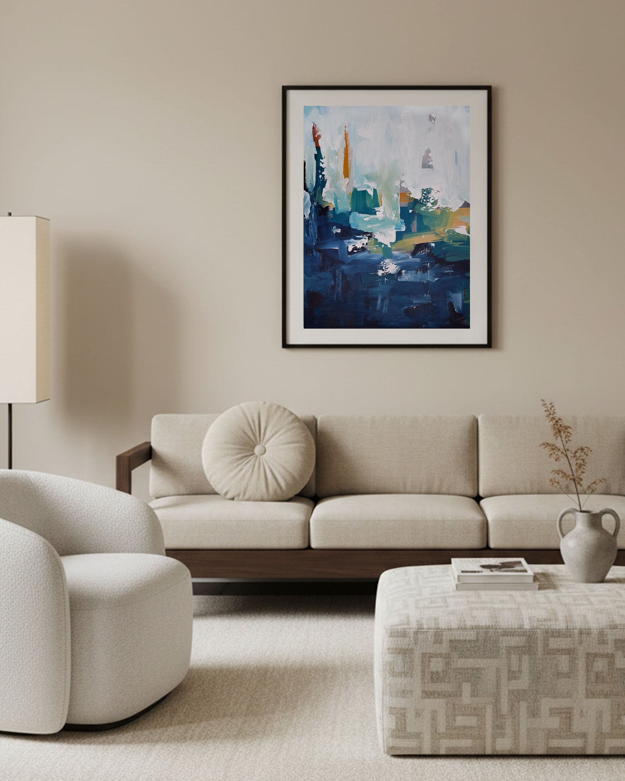 Pared down living room interior with bespoke cream storage coffee table and cream sofa with round cushion and large abstract wall art prints on wall