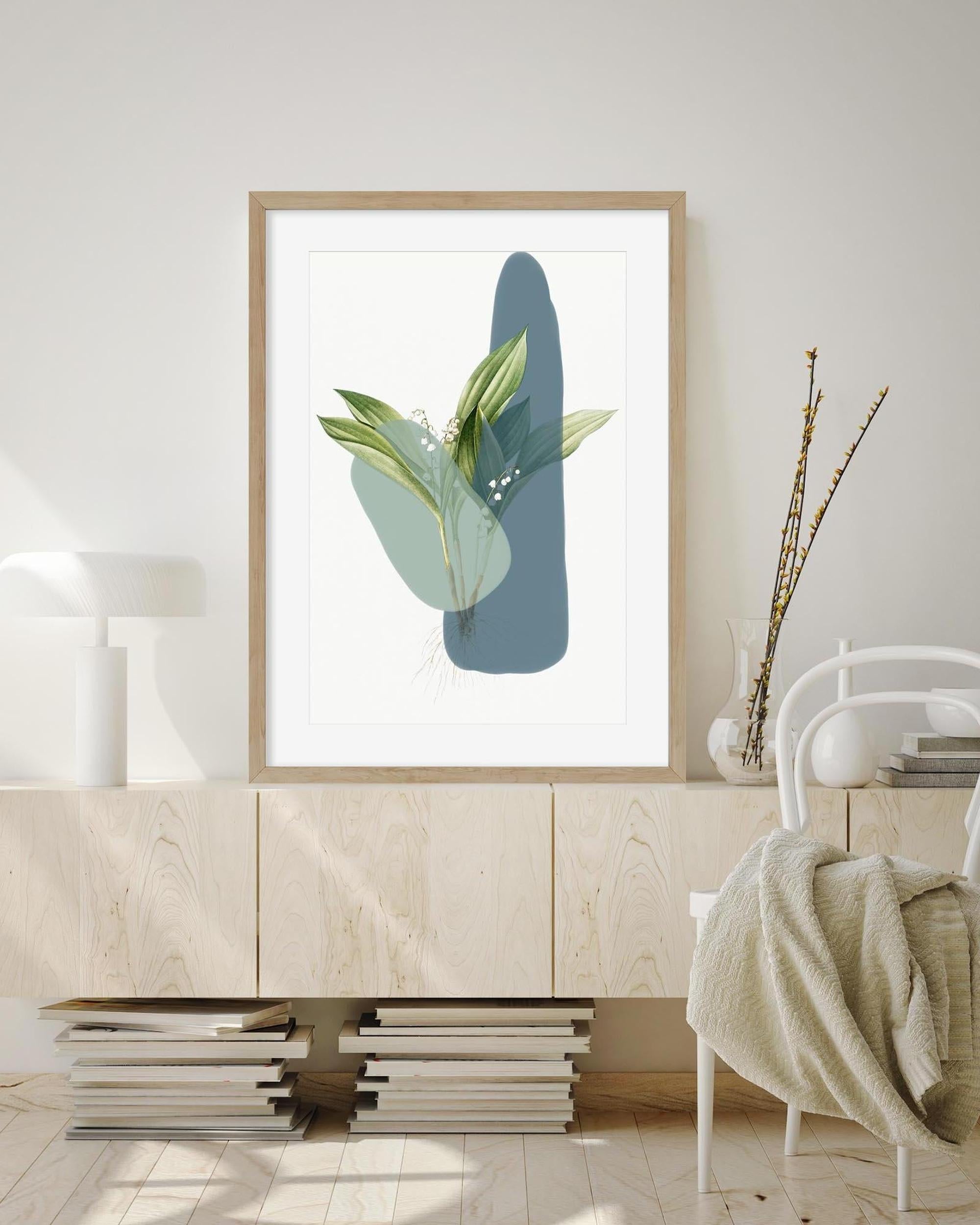 Framed artwork with green leaves and blue abstract shapes on a wall in a room.