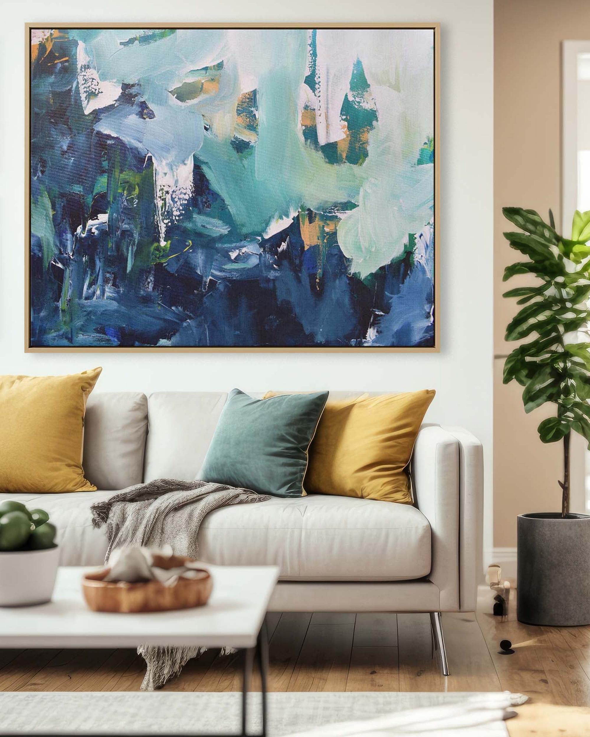 Living room with a large abstract painting on the wall, a white sofa with colorful cushions, and a plant.