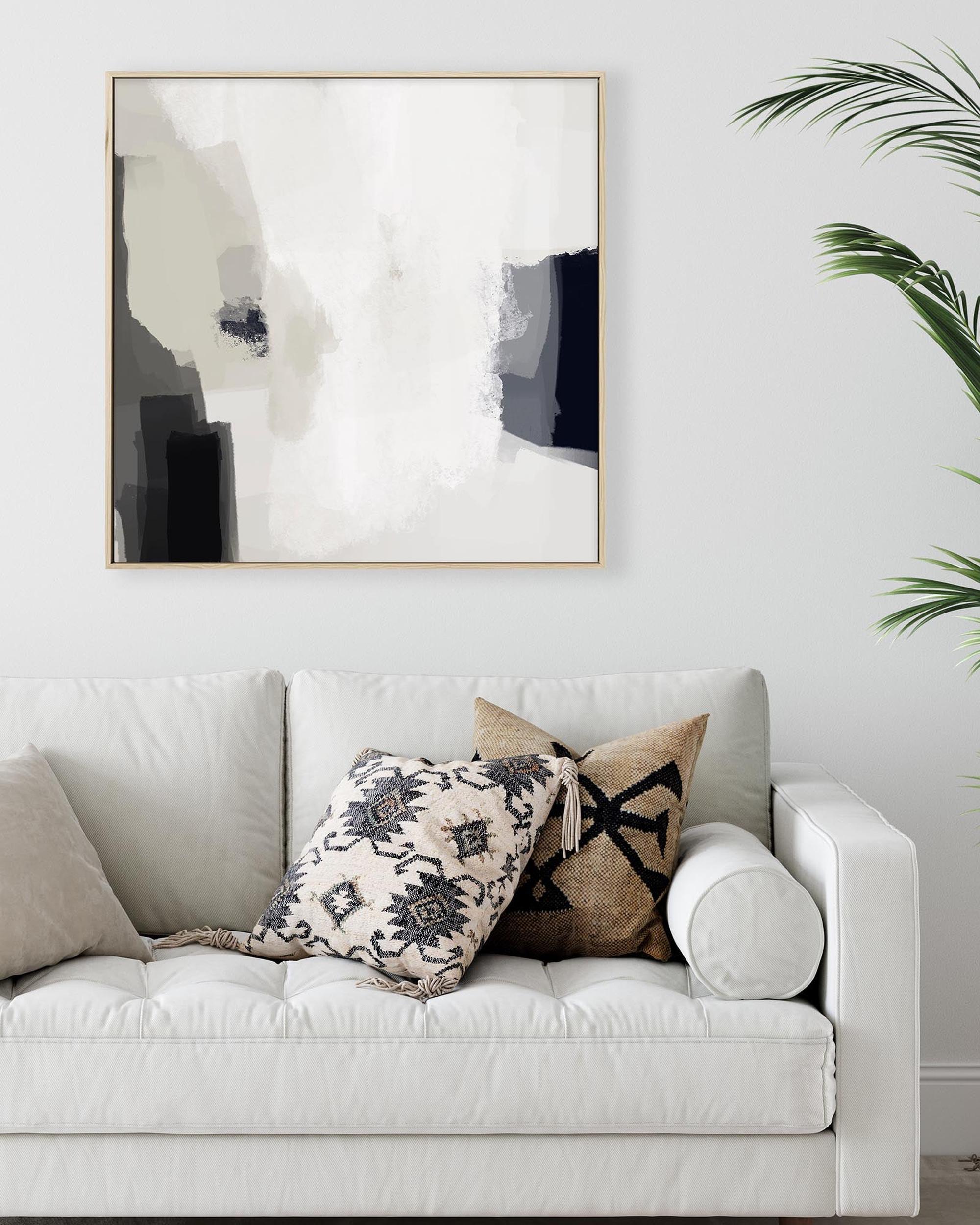 White sofa with decorative pillows and abstract art on the wall