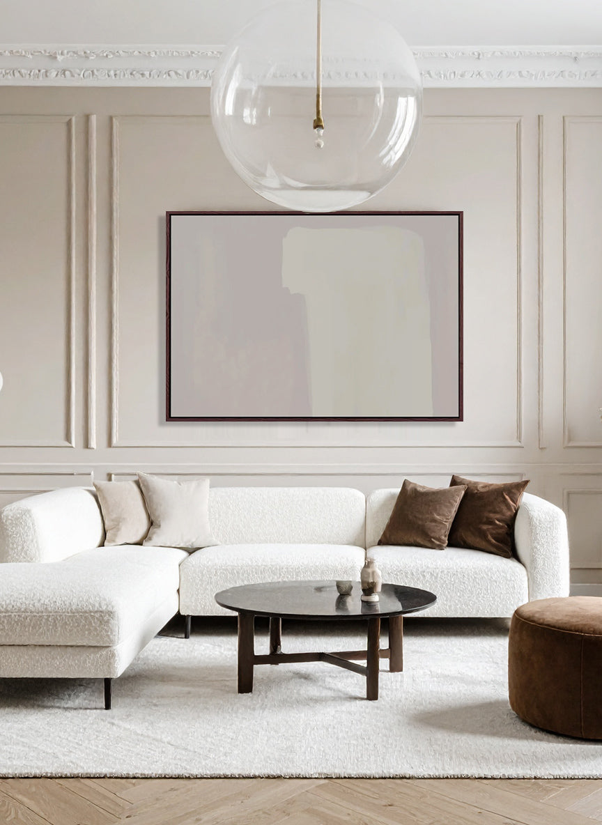 Modern living room with a white sofa, brown pouf, and round coffee table.