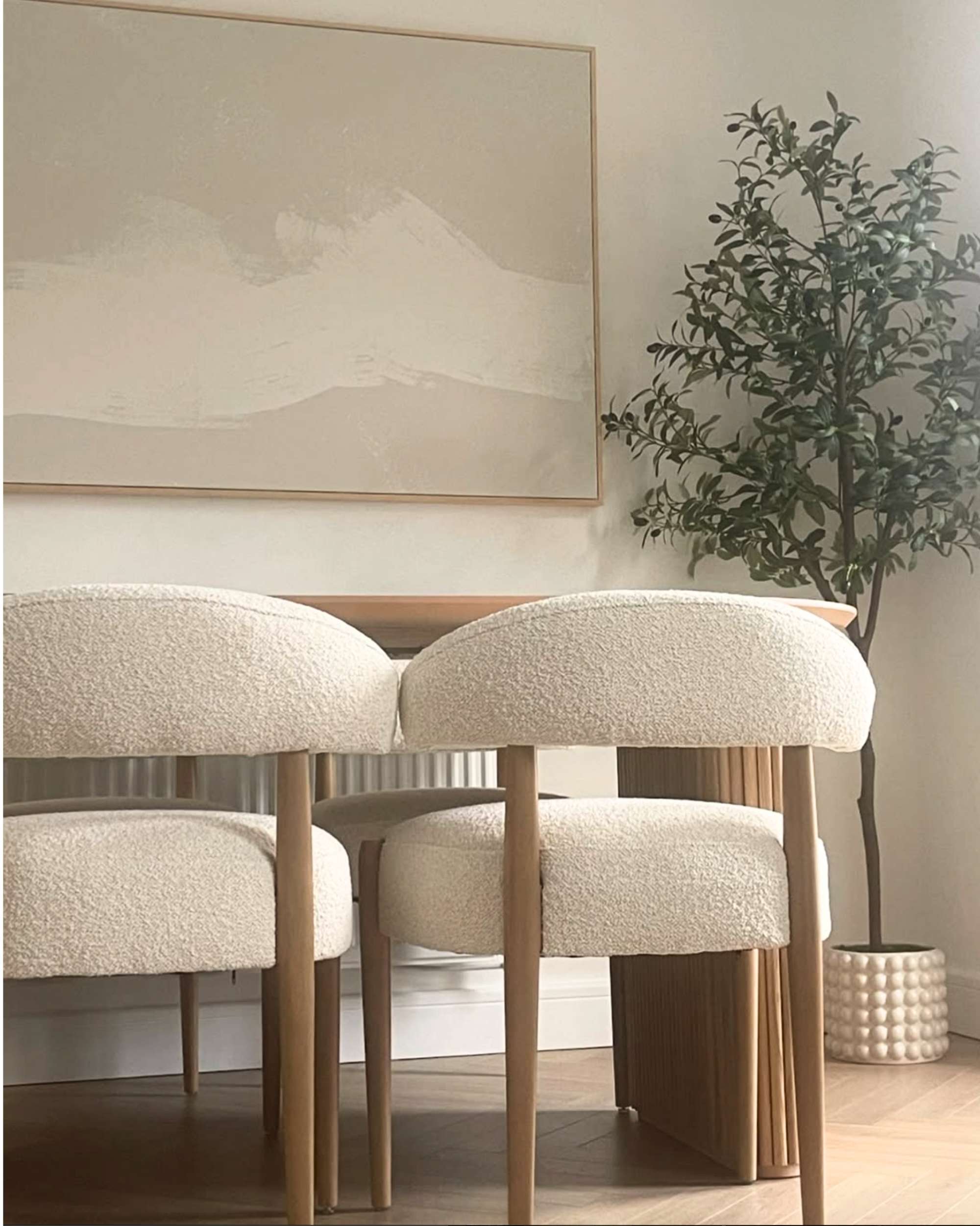 A framed canvas abstract art piece depicting neutral Sands, displayed on a wall above a pair of chairs in a well-decorated interior room.