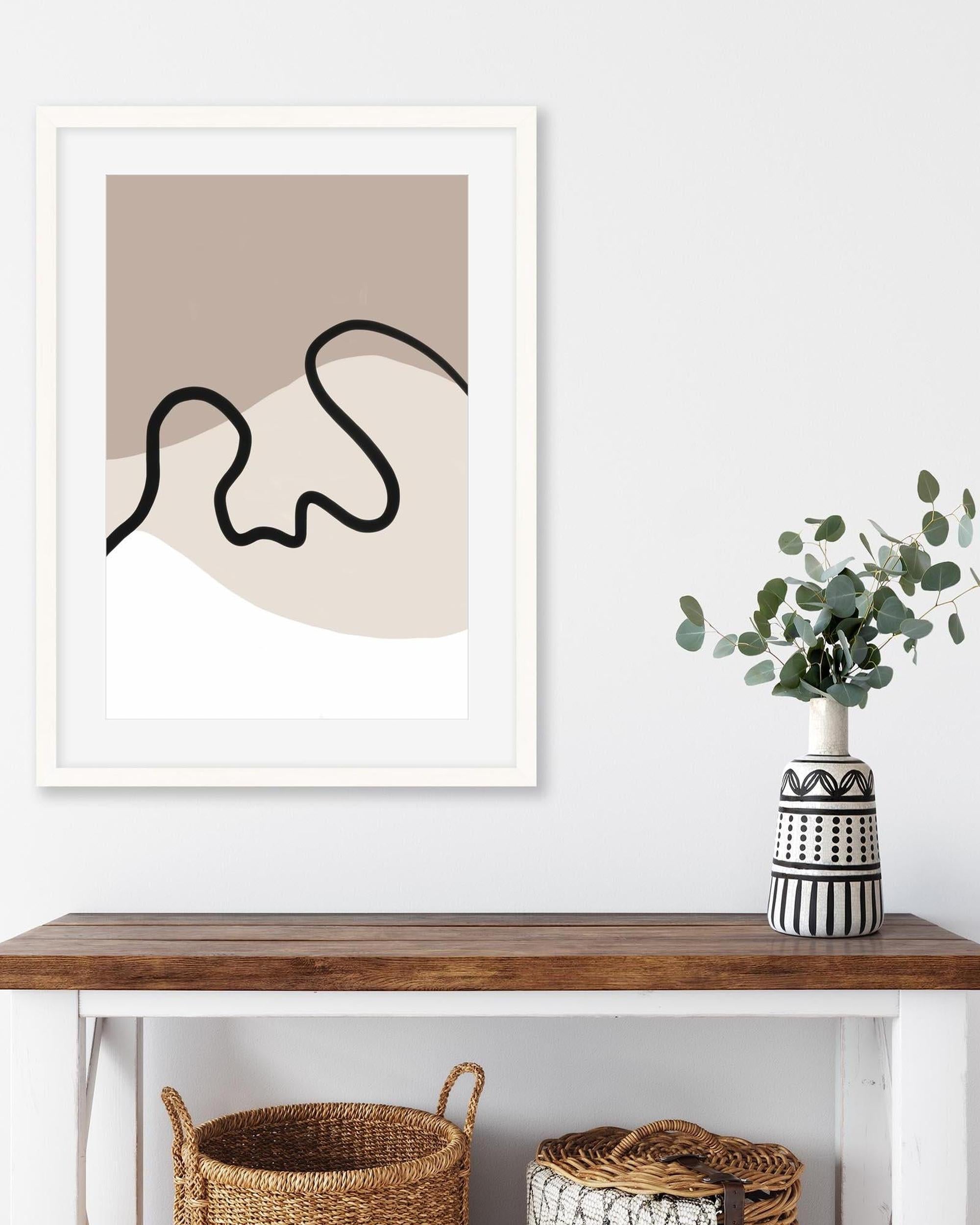 Framed abstract art print on a wall above a wooden console table with decorative items.
