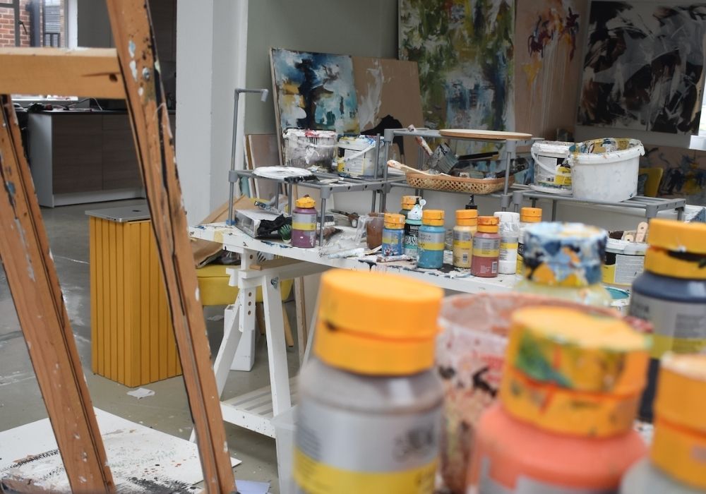 Original art supplies including paint pots and a palette in an artist's studio.
