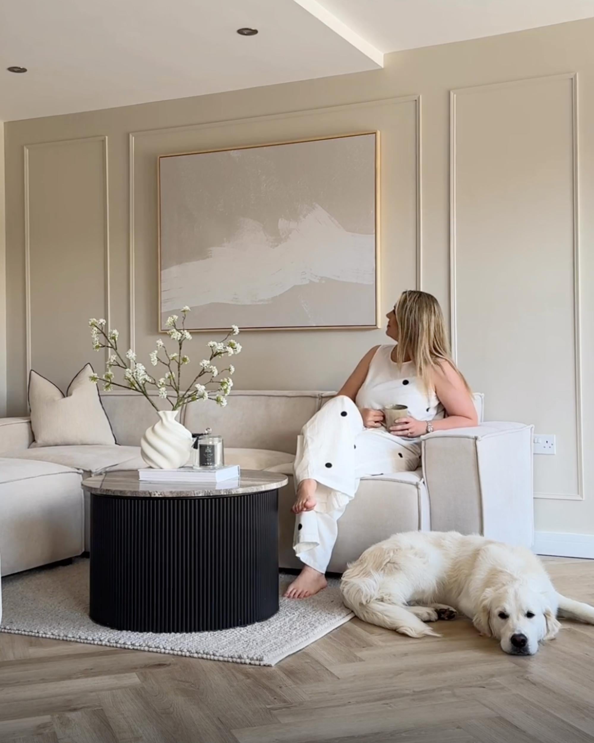 Woman sitting on a chair with a dog on the floor in a modern living room.