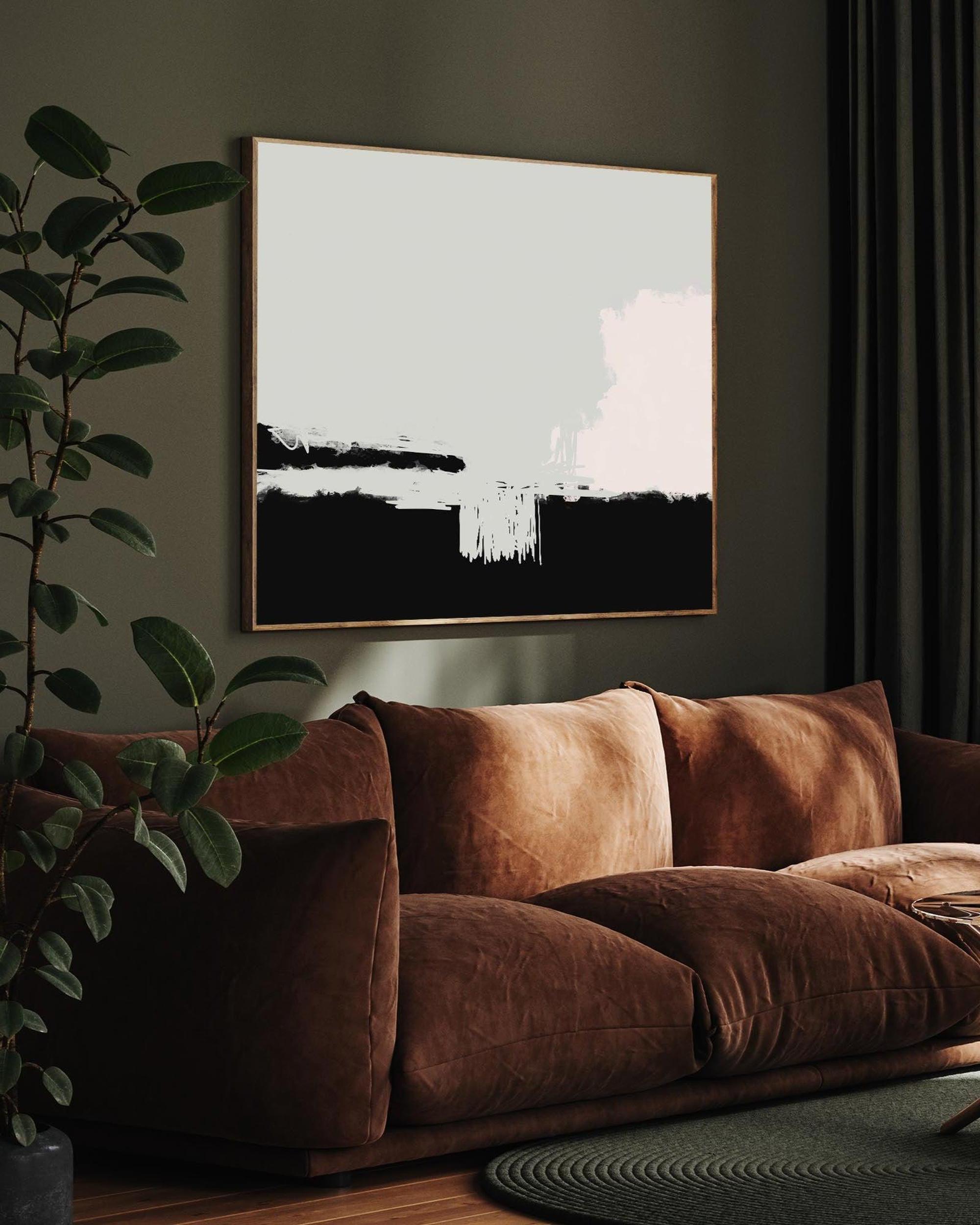 Brown sofa with a plant and abstract art on a wall in a living room.