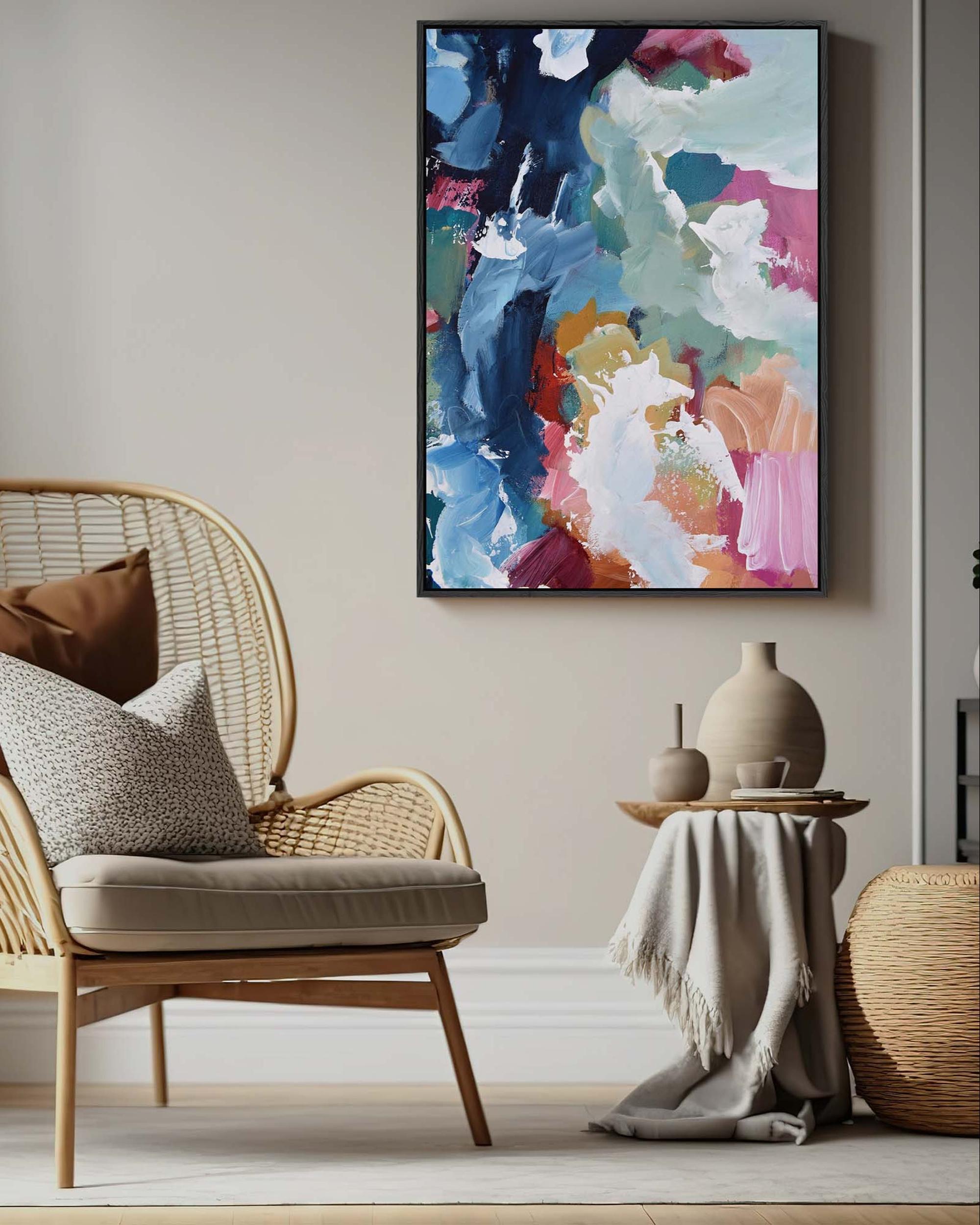 Wicker chair with cushions in a room with a colorful abstract painting on the wall.