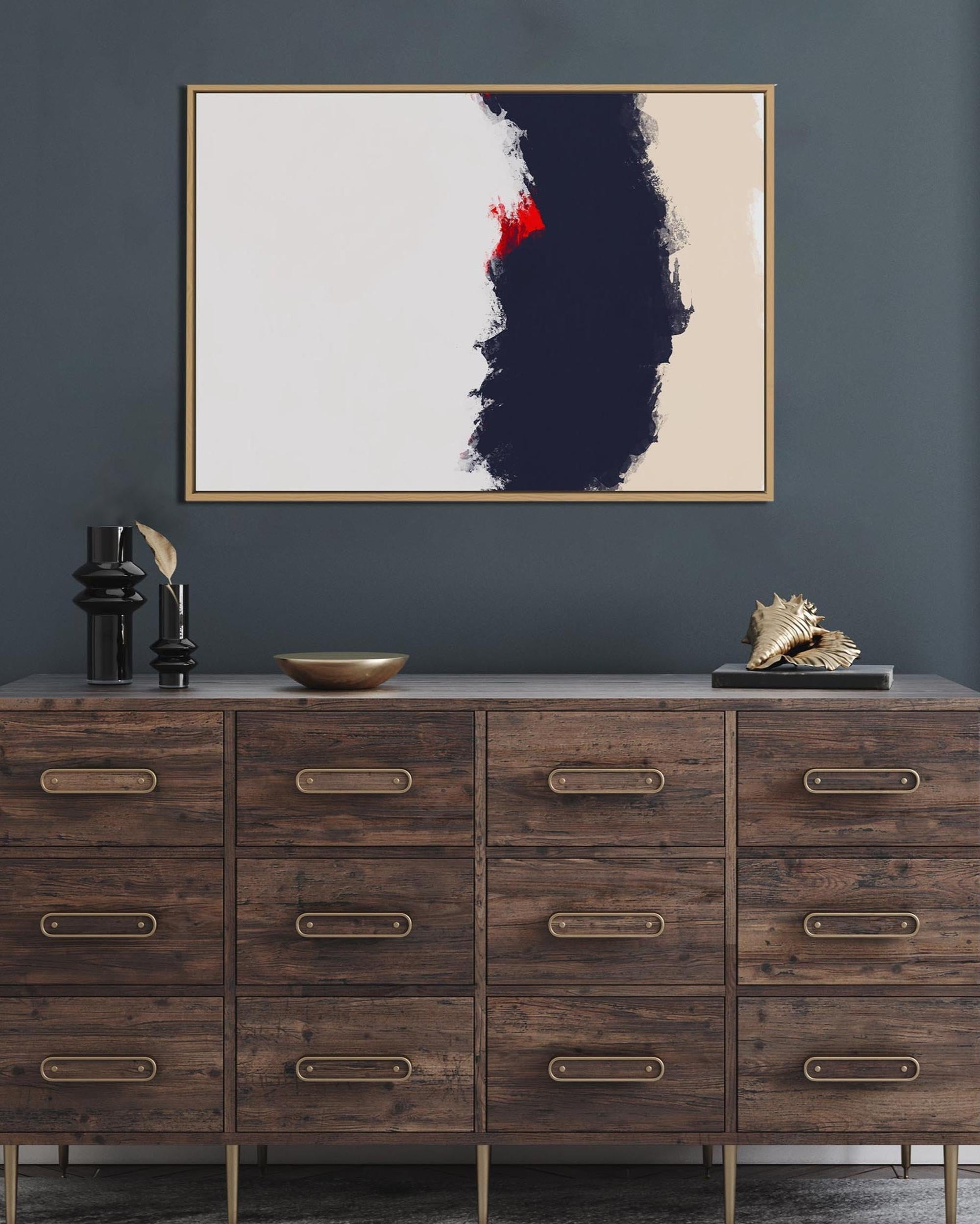 Wooden dresser with decorative items against a dark gray wall with a framed abstract painting.