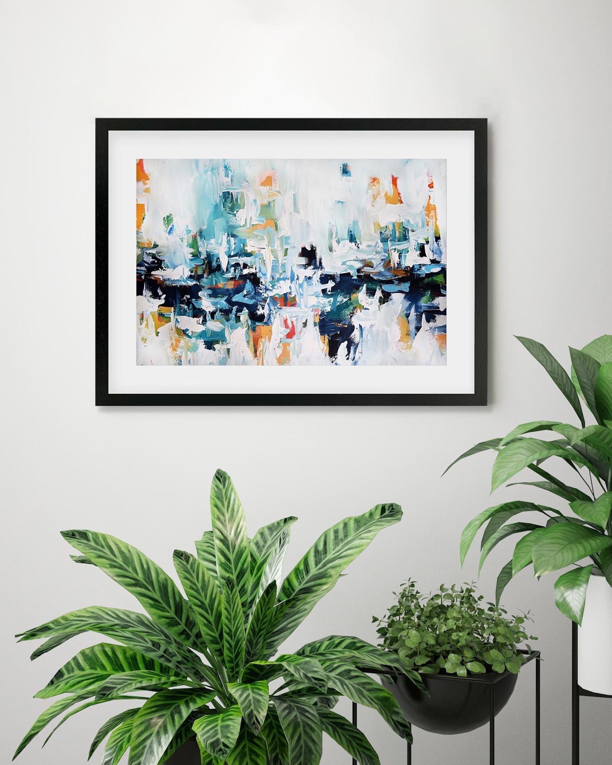 Framed abstract art piece on a wall with potted plants below.