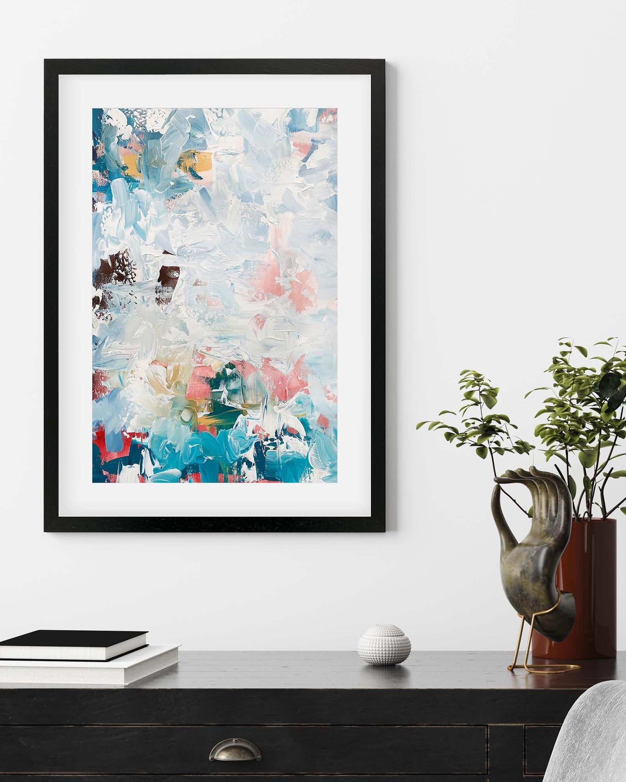 Framed abstract art piece on a wall above a desk with decorative items.
