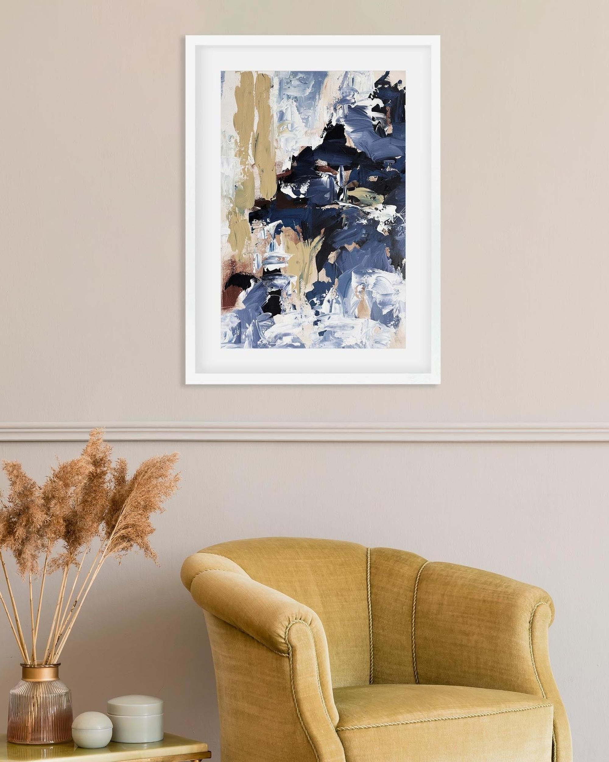 Abstract art print on a wall above a mustard yellow armchair.