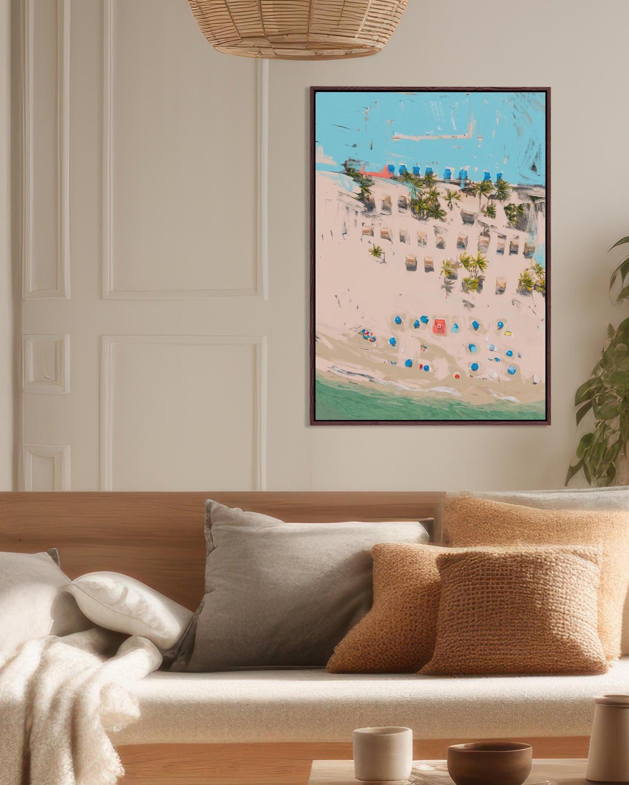 Framed artwork of a coastal scene with buildings and beach chairs on a wall above a sofa.