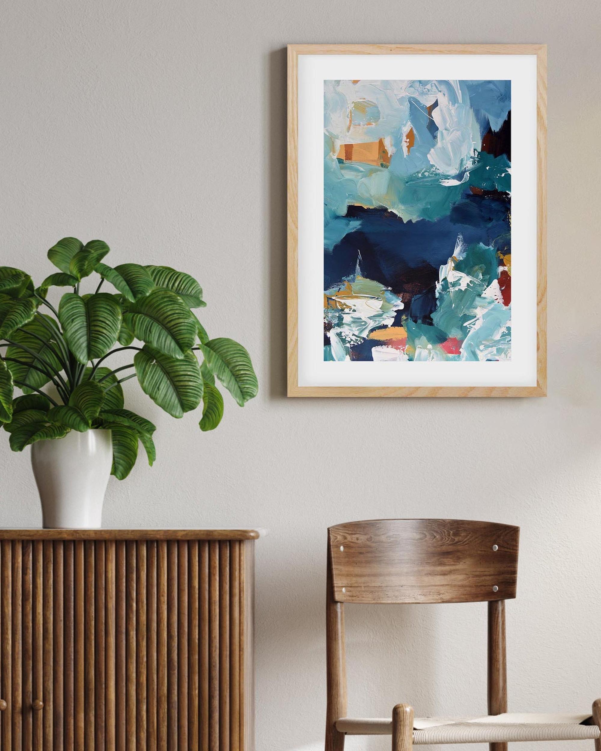 Room interior with a plant on a wooden cabinet, abstract art on the wall, and a chair.