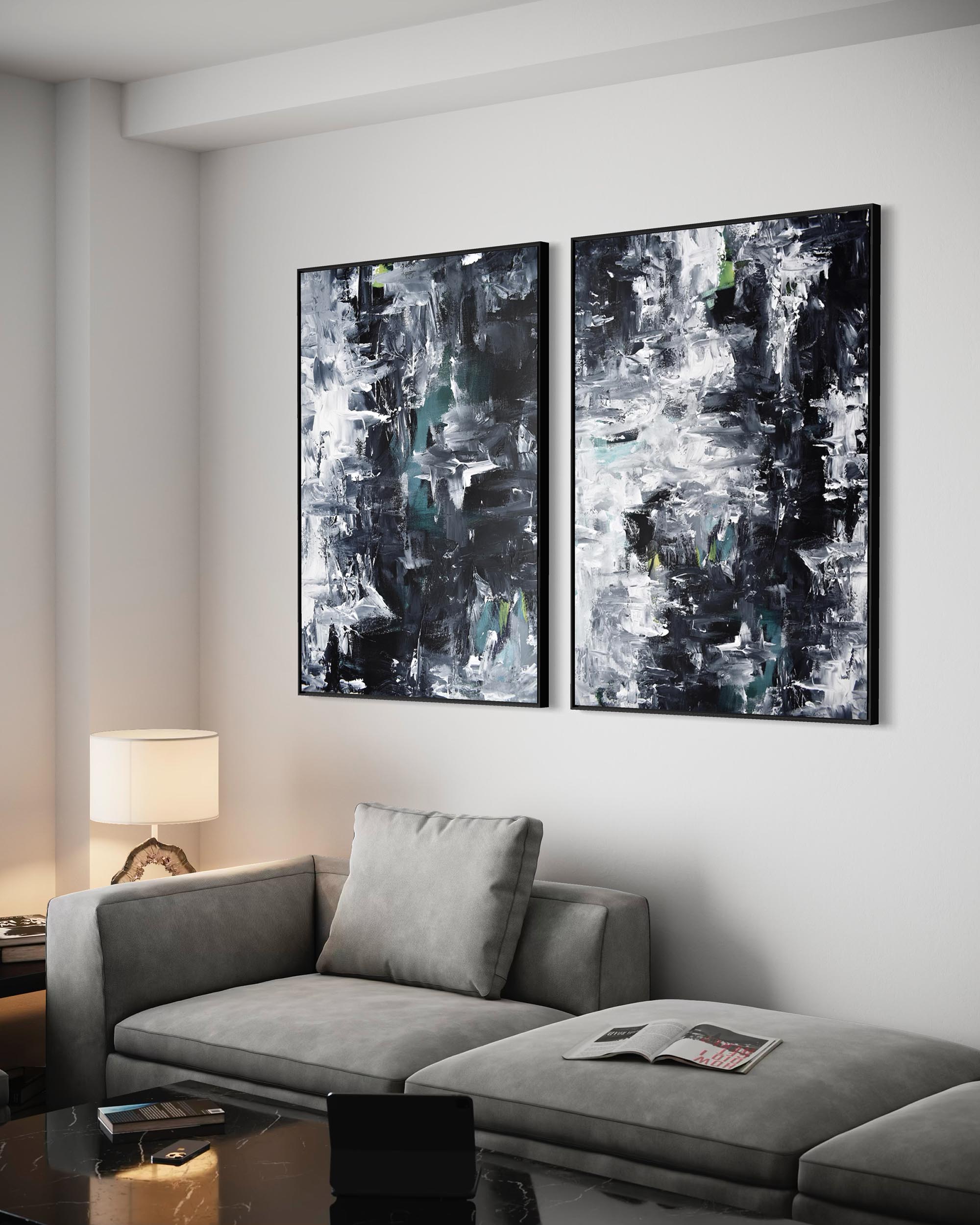 Two abstract paintings on a wall above a gray sofa in a living room.