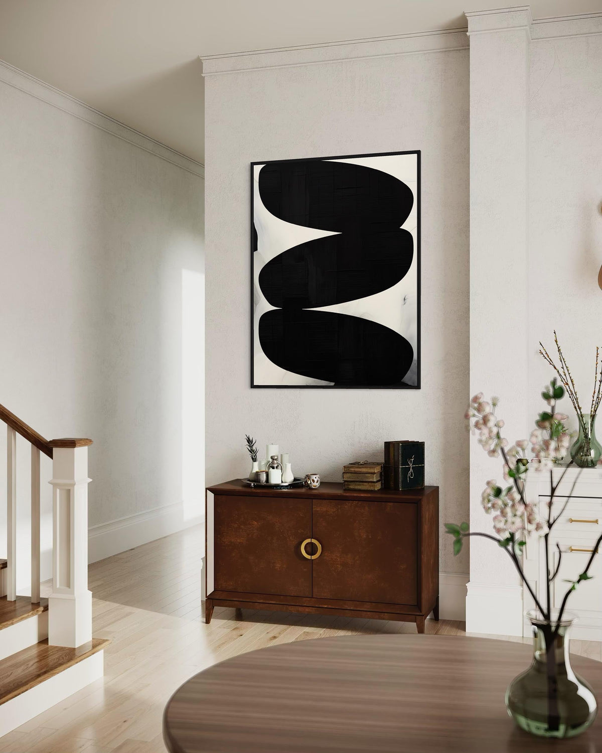 Modern interior with abstract black and white artwork on a wall above a wooden cabinet.