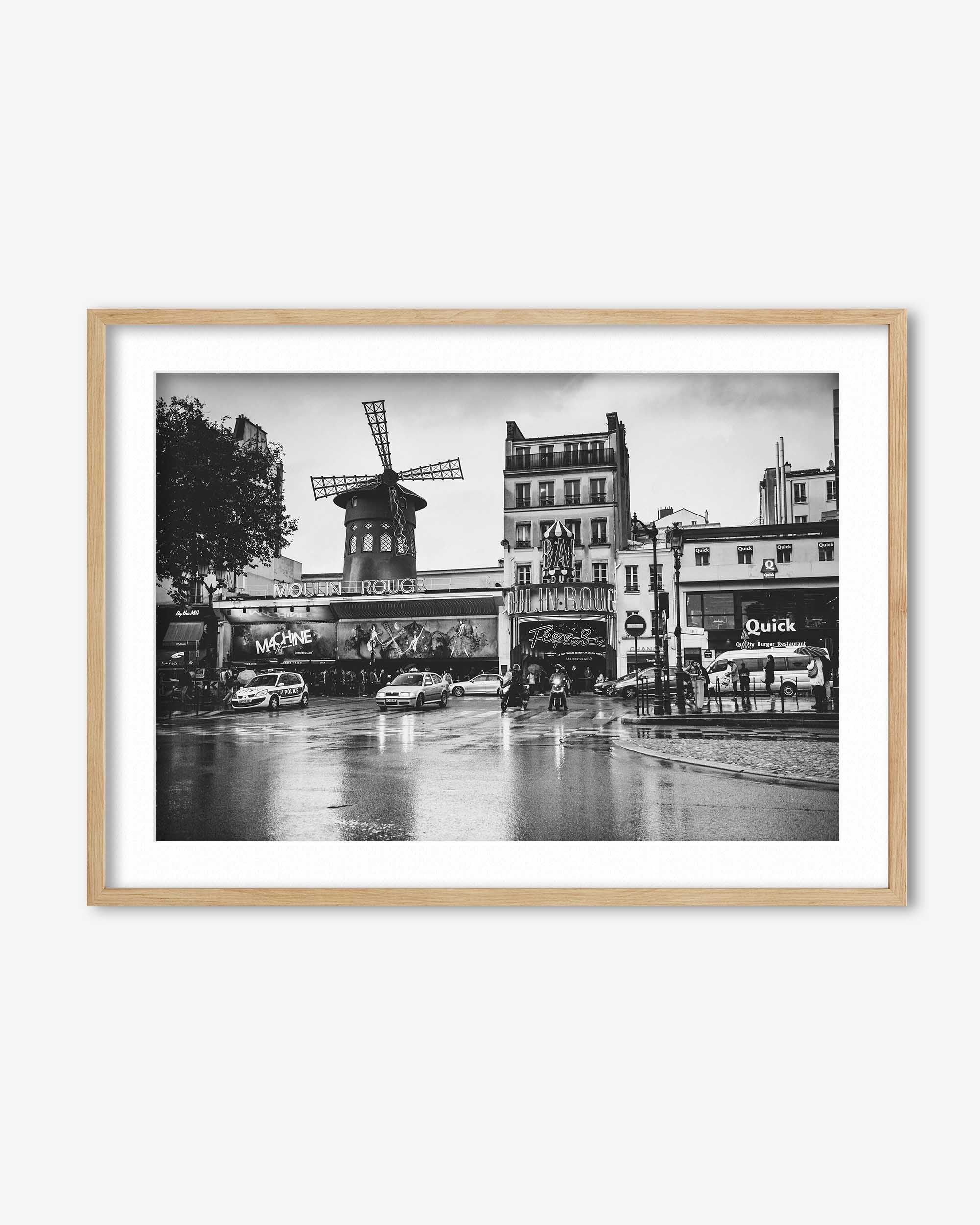 Framed black and white photo of a city street with a windmill, cars, and buildings.