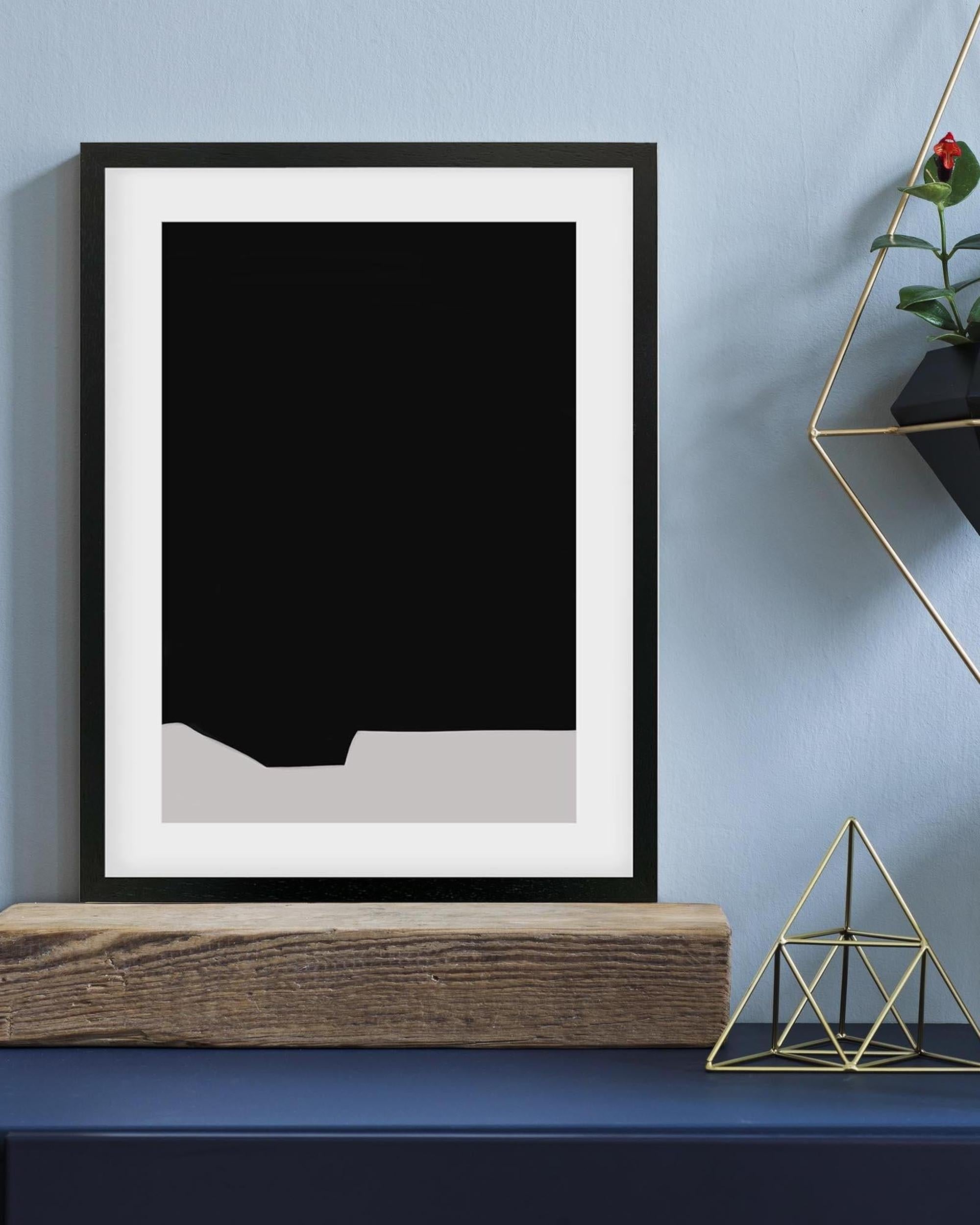 Framed black and white abstract art piece on a blue wall with decorative elements.