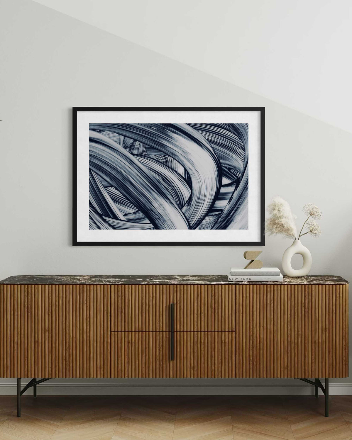 Framed abstract art above a wooden sideboard with decorative items.