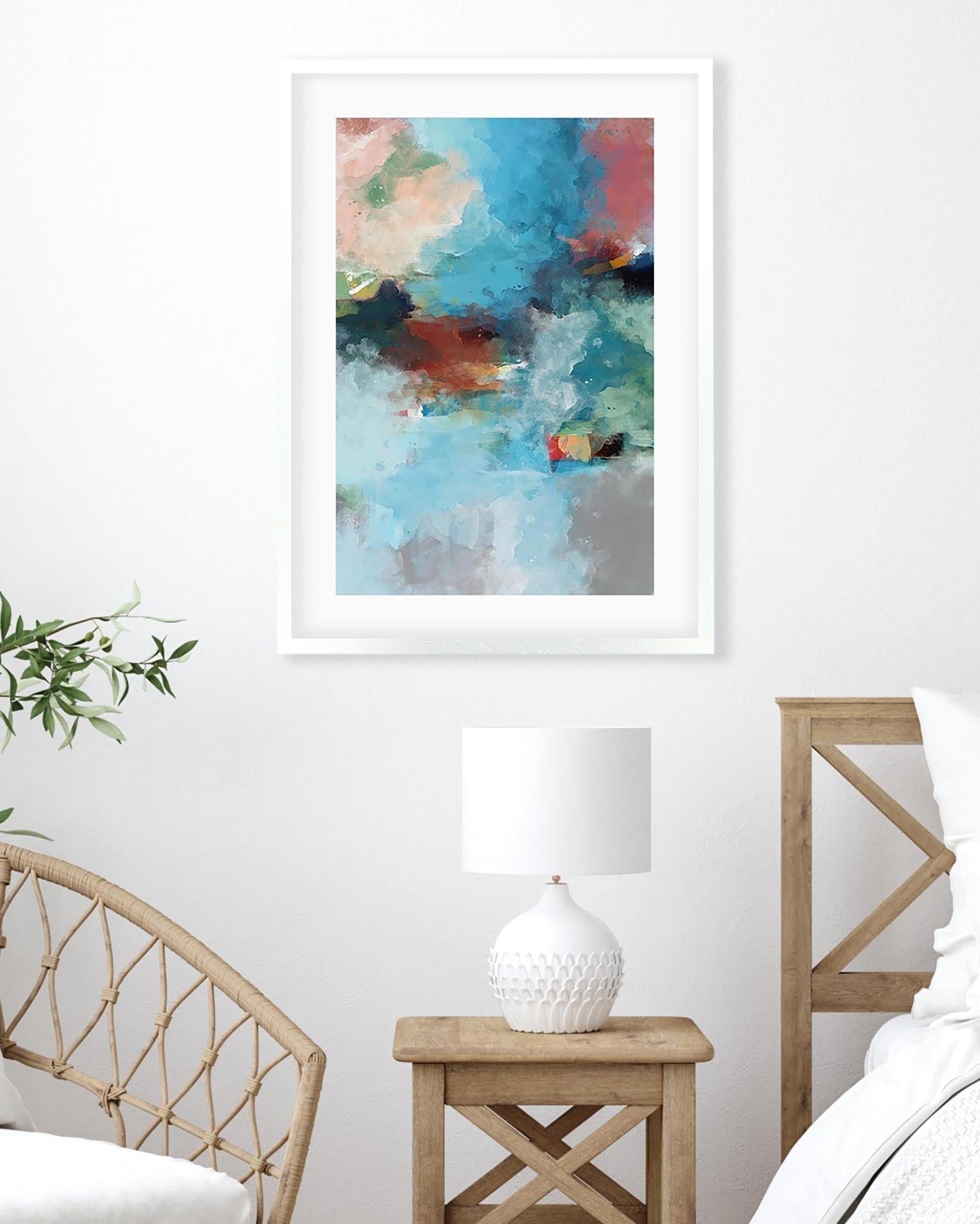 Framed abstract painting on a wall above a wooden side table with a lamp and chair.