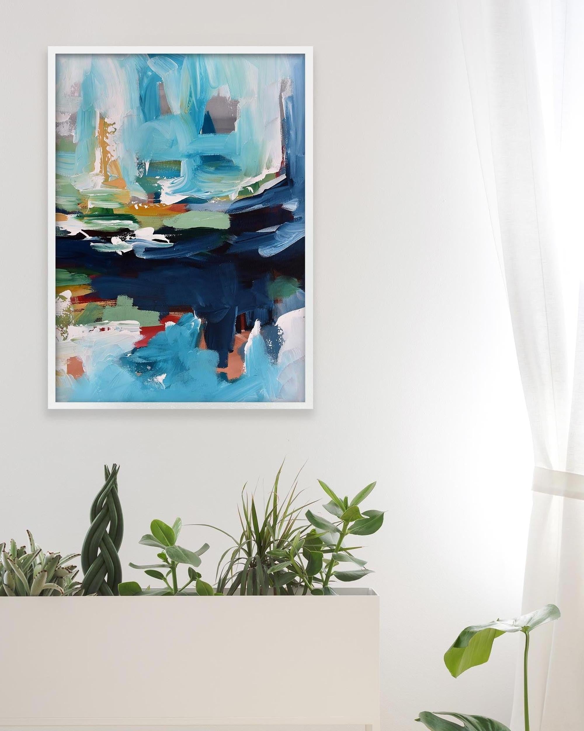 Abstract painting with blue and green tones on a white wall above a white cabinet with plants.
