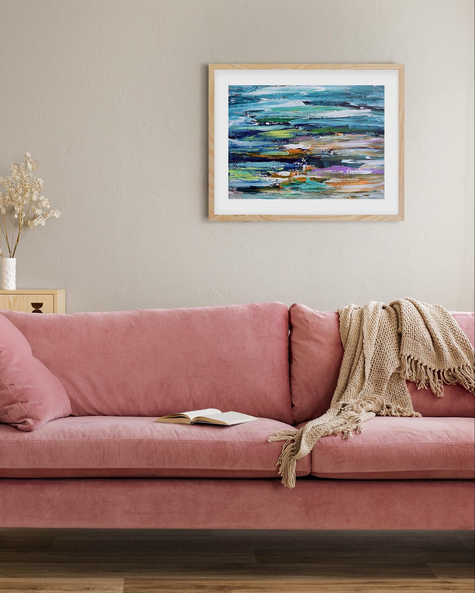 abstract seascape framed print in living room above a pink modern sofa