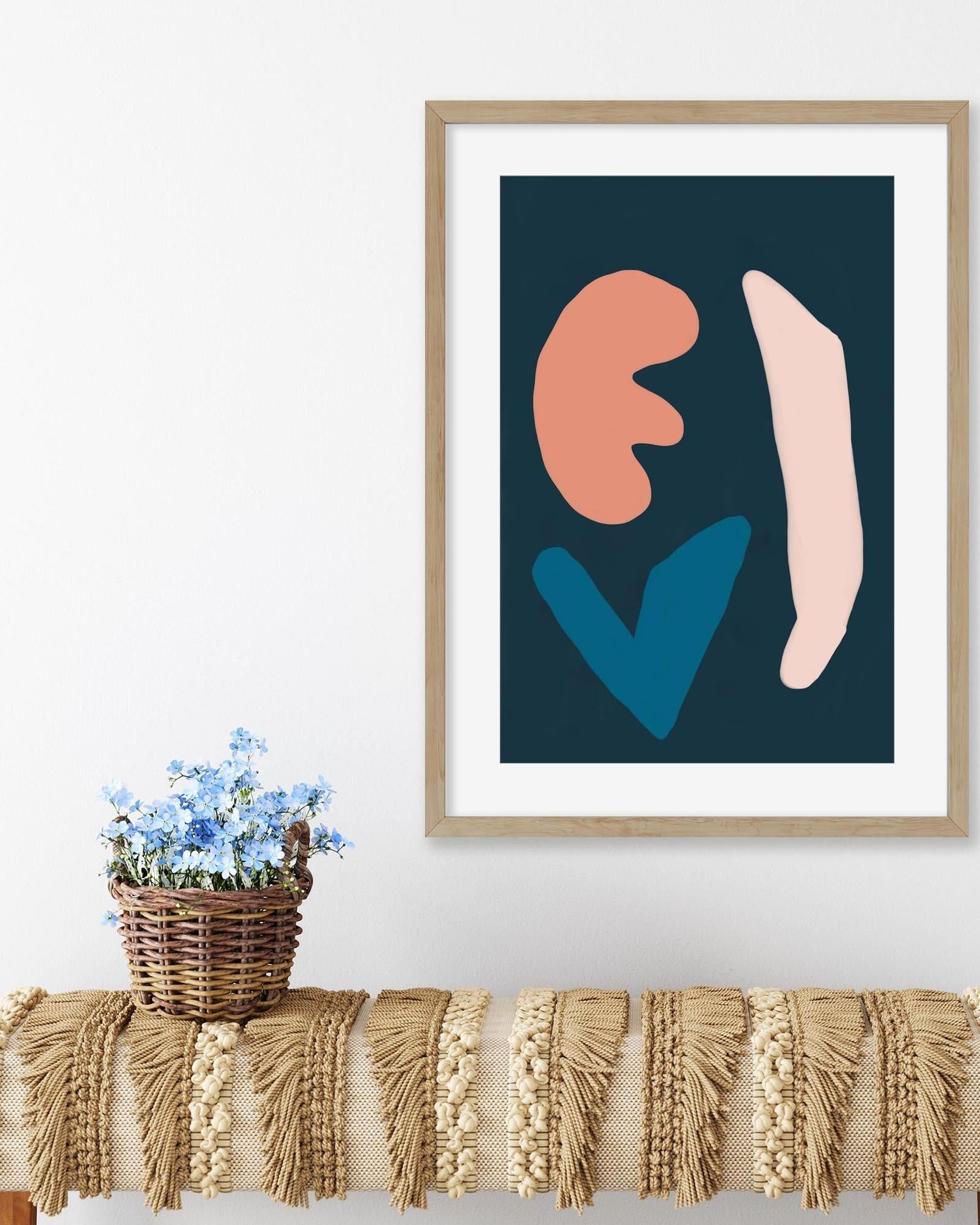 Framed abstract art print on a wall above a table with a textured runner and basket of flowers.