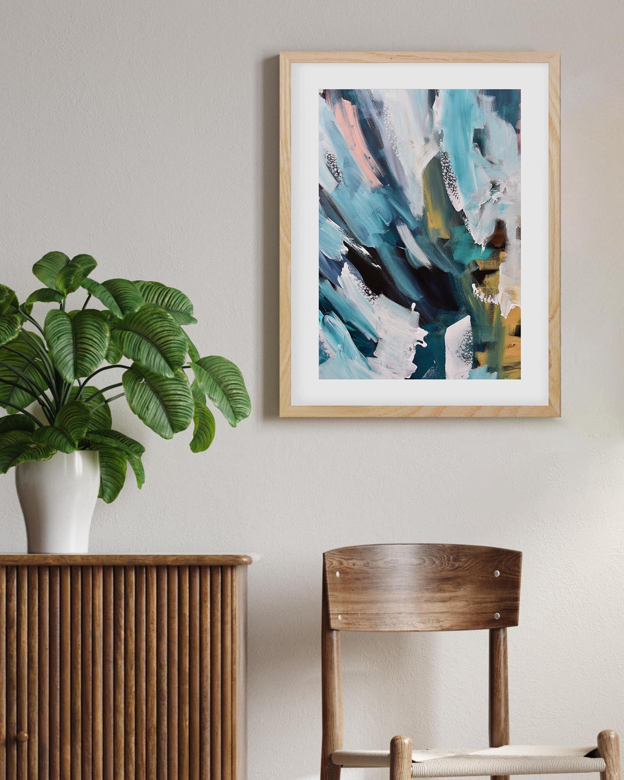 Modern interior with a plant, wooden cabinet, and abstract art on the wall.