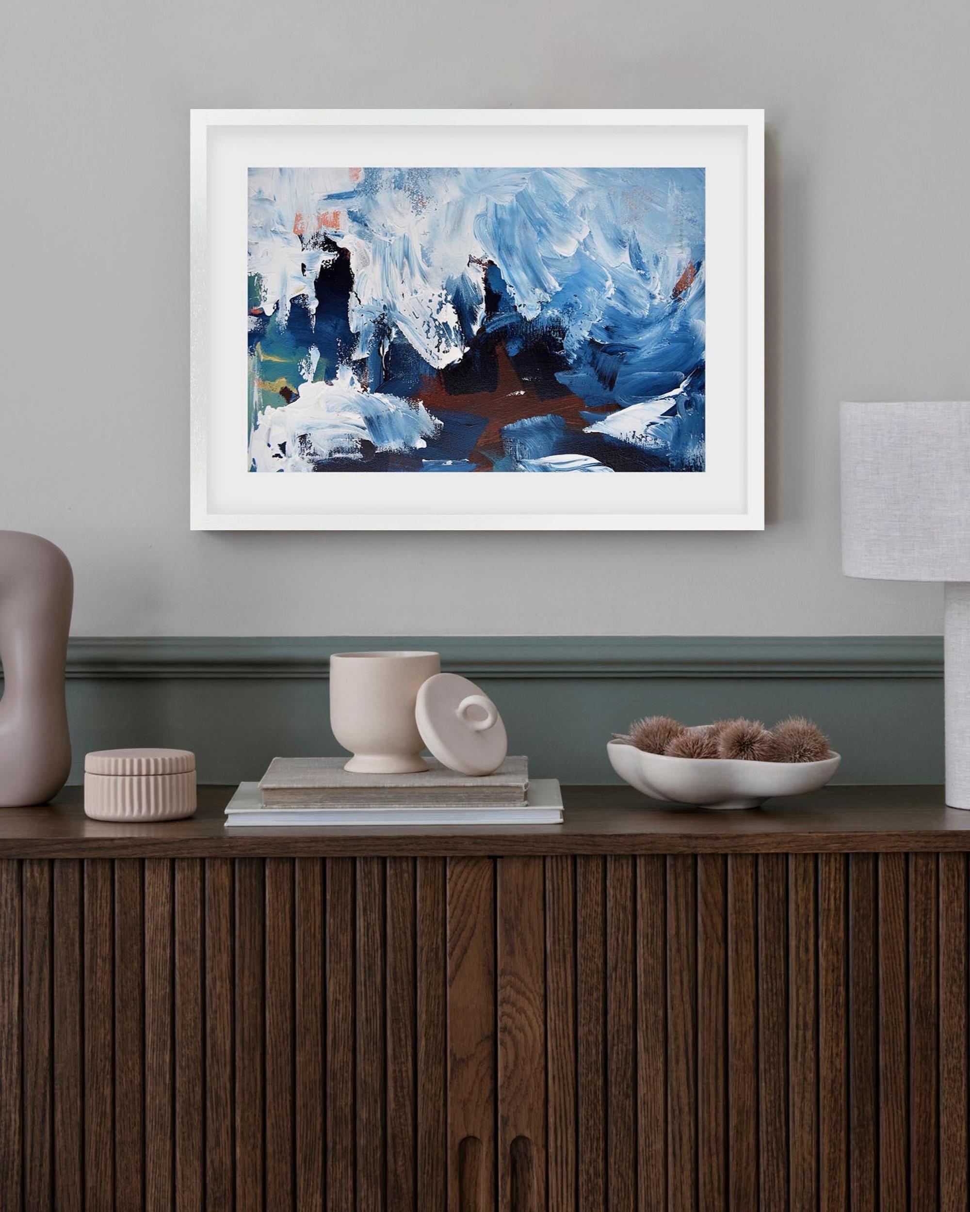 Framed abstract painting on a wall above a wooden console table with decorative items.