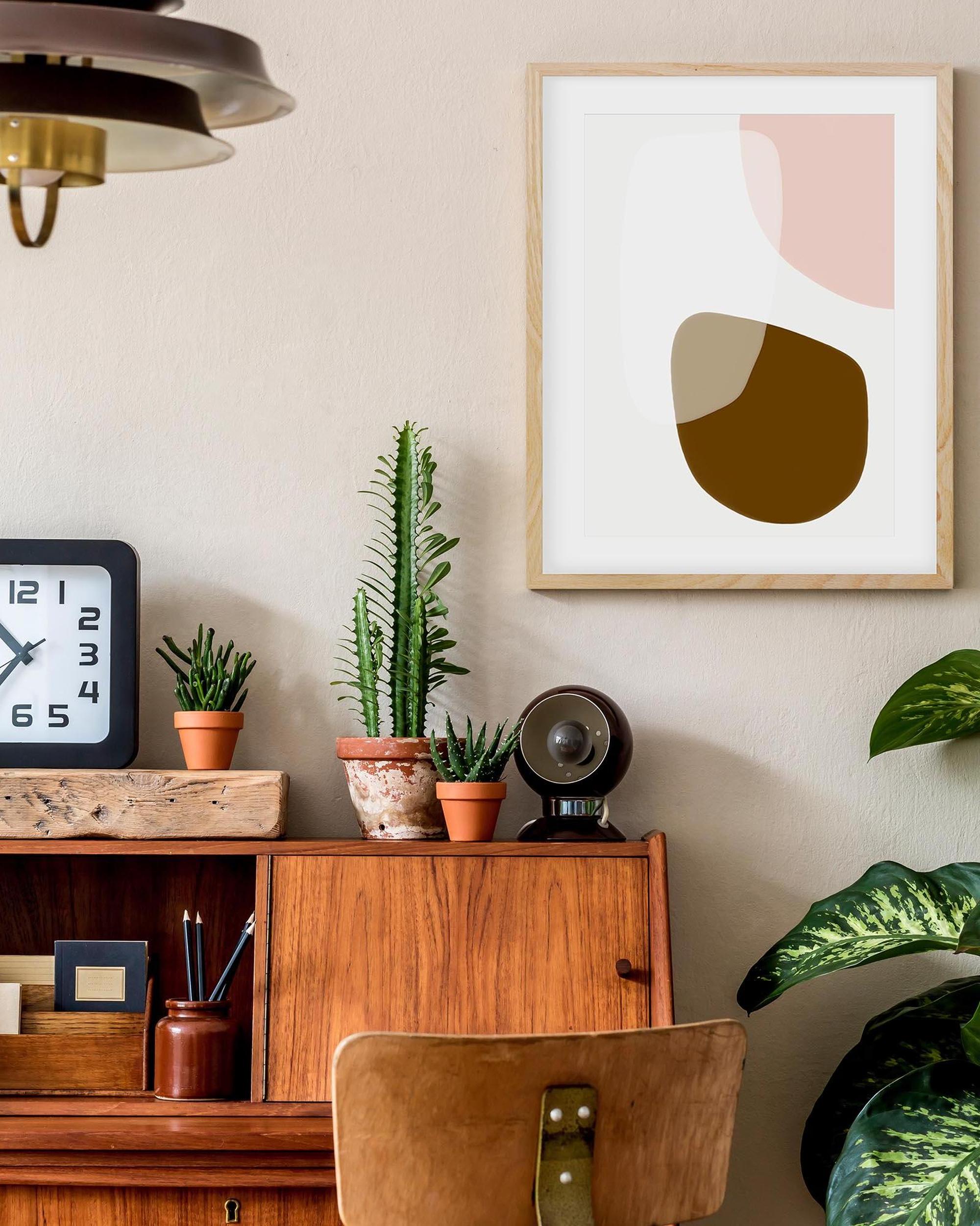 Home office with wooden desk, plants, and abstract art on wall