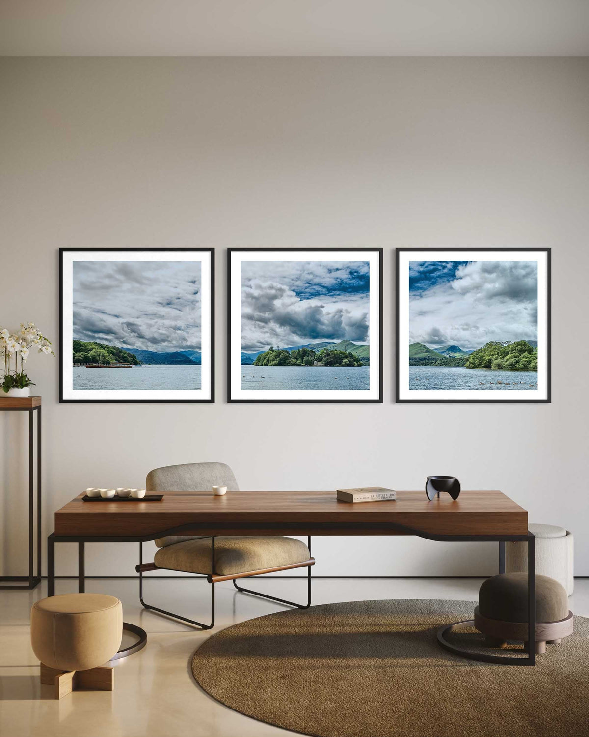 Three framed landscape pictures above a wooden desk in a modern office setting.