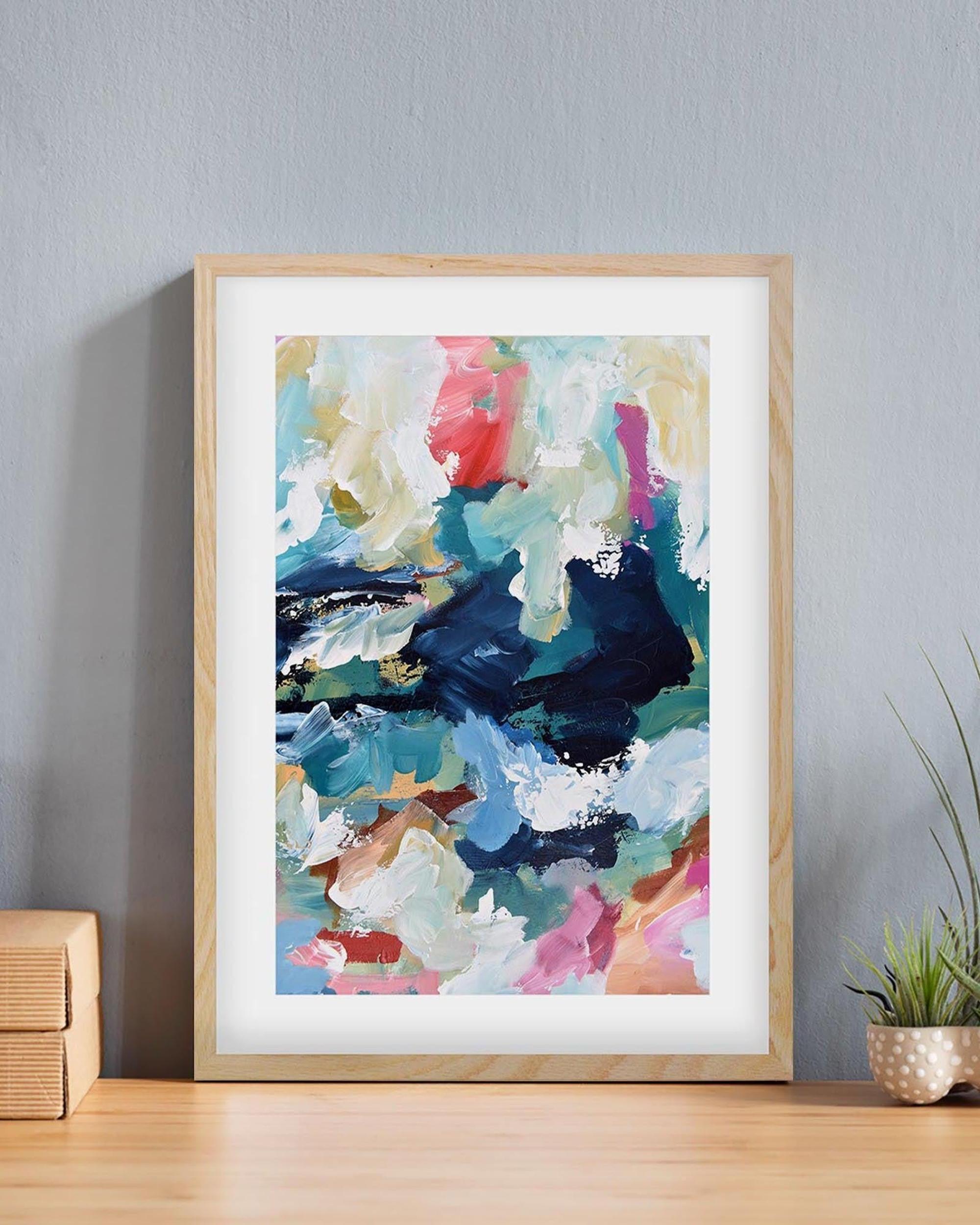 Framed abstract painting with colorful brushstrokes on a gray wall.