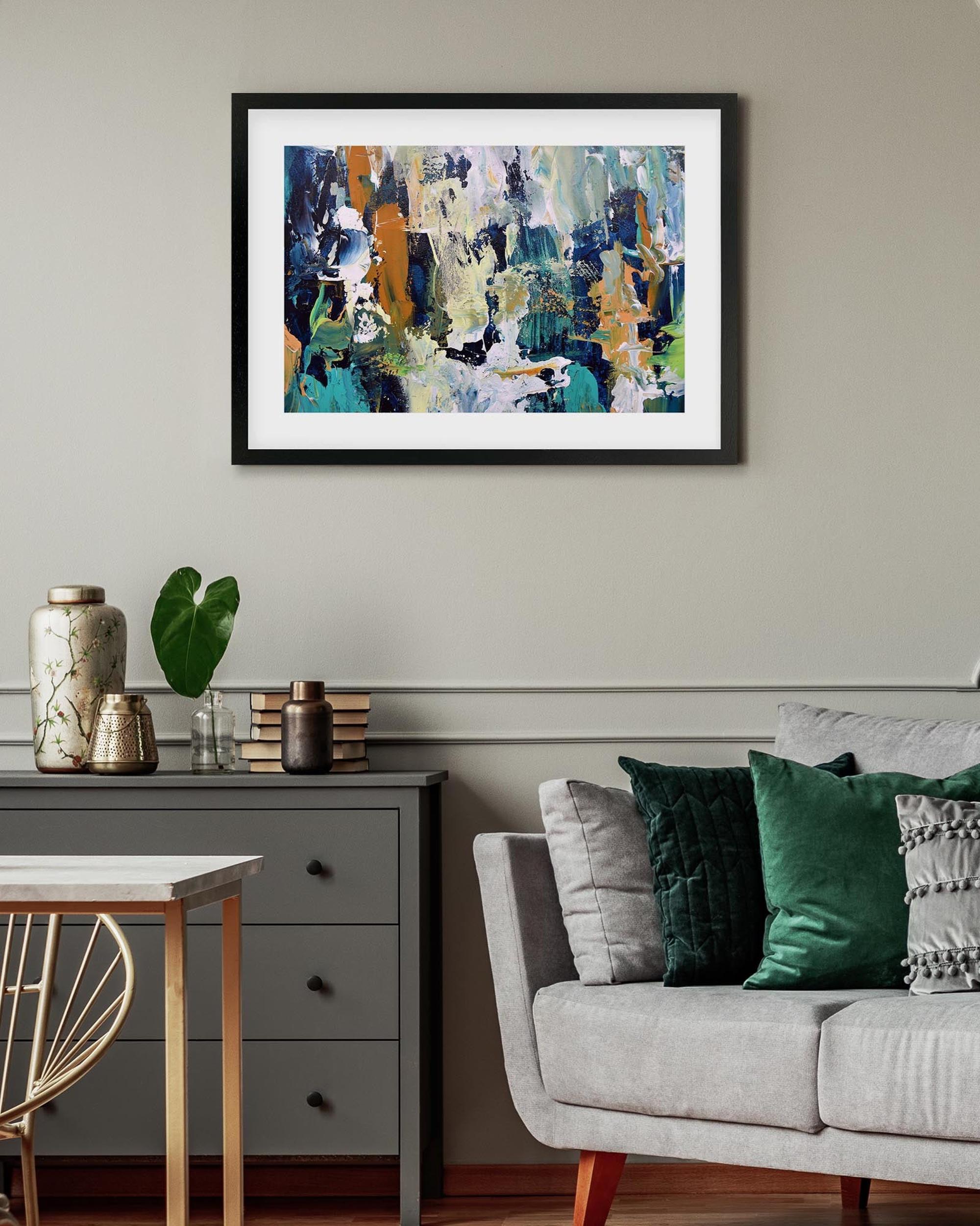 Framed abstract painting on a wall above a sofa and side table in a living room.