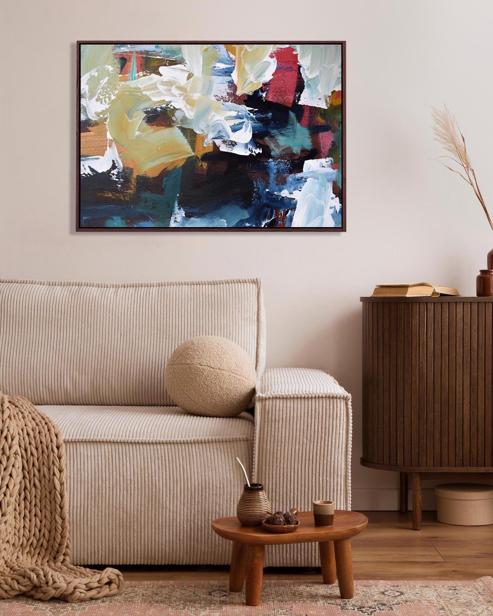 Living room with a beige sofa, wooden side table, and abstract painting on the wall.
