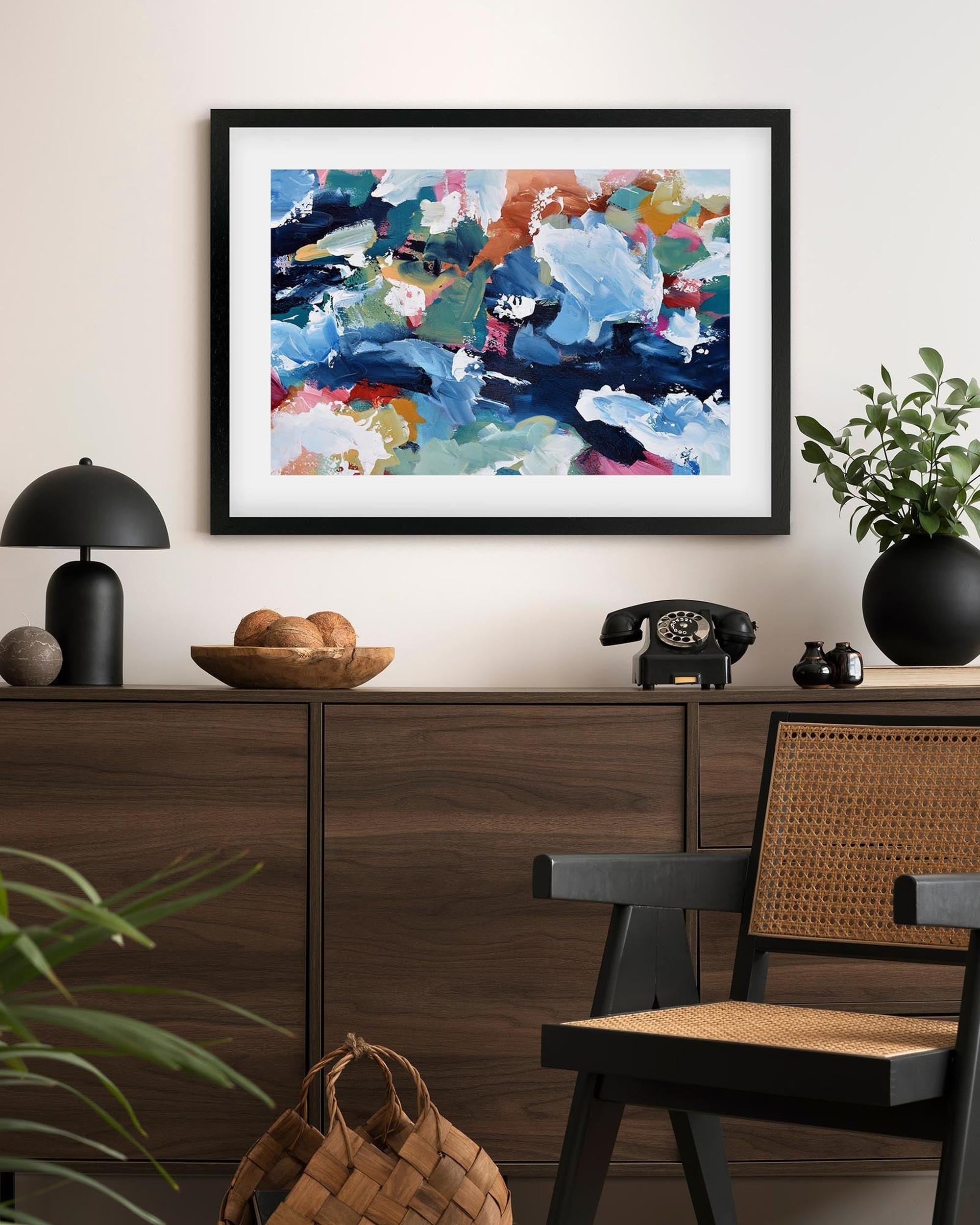Abstract art print on a wall above a wooden console table with decorative items.