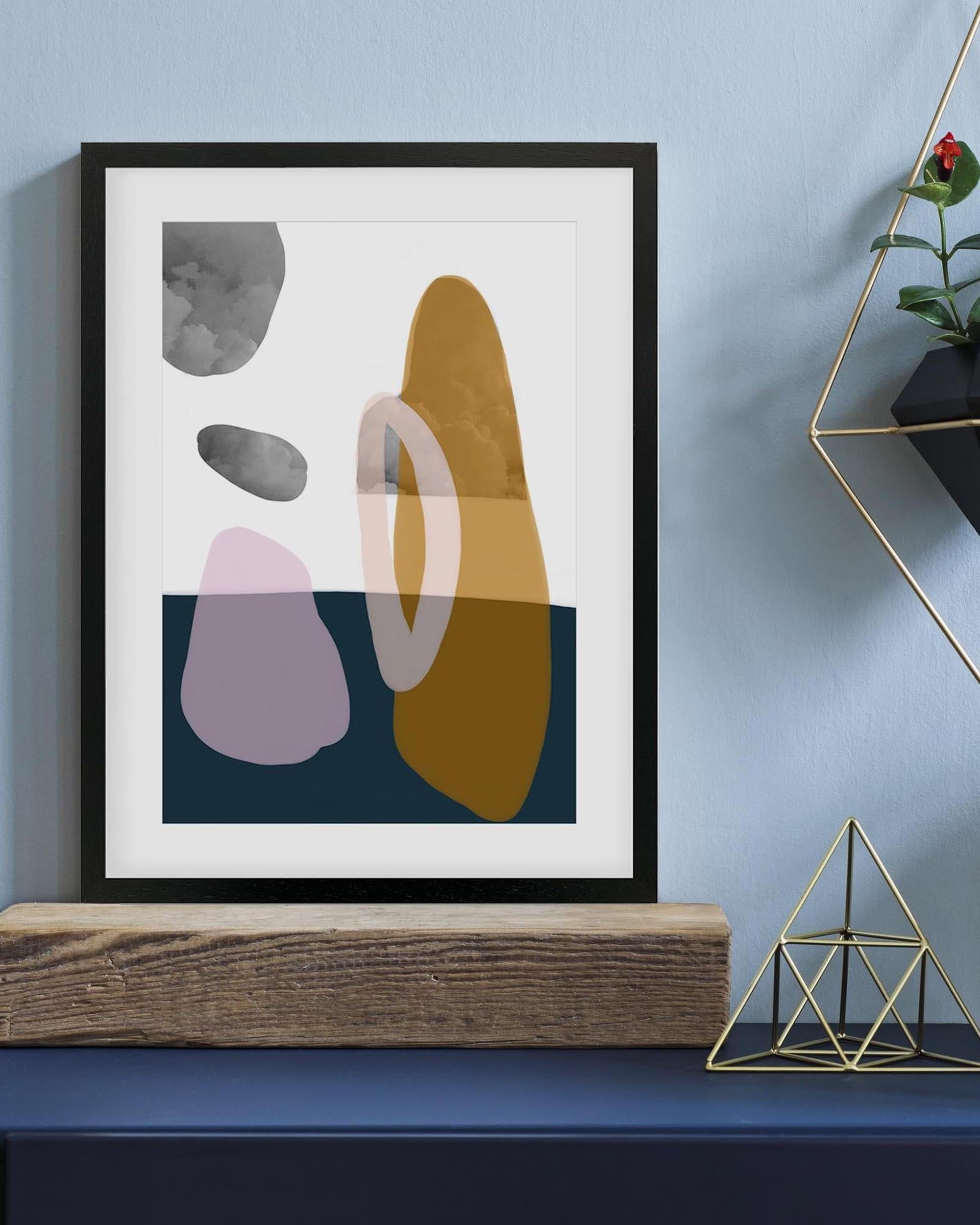 Abstract art print with geometric shapes in a black frame on a blue wall.