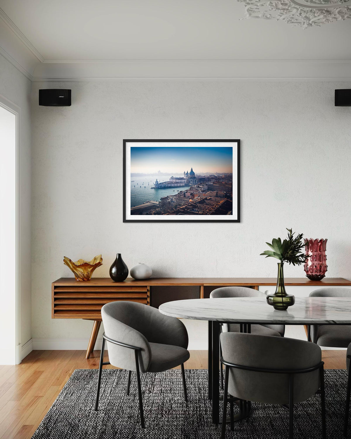 Dining room with a framed picture of a cityscape on the wall, wooden table, and chairs.