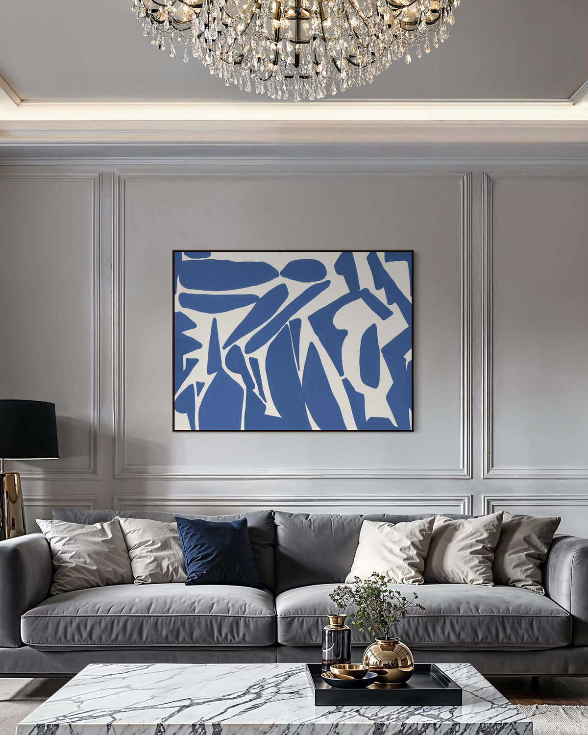 Modern living room with gray sofa, abstract blue and white painting, and chandelier.
