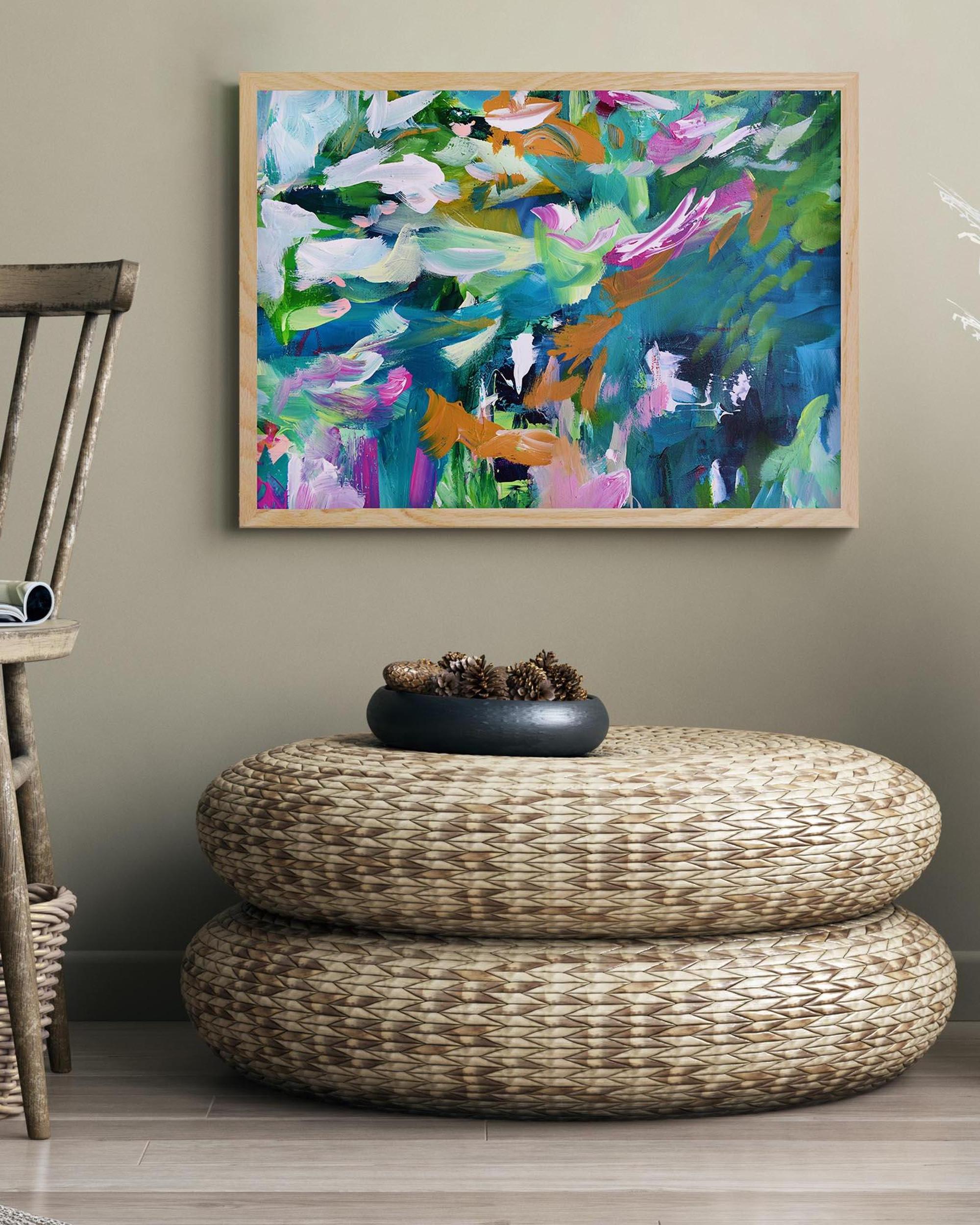 Colorful abstract painting on a wall above a woven ottoman with a decorative bowl.